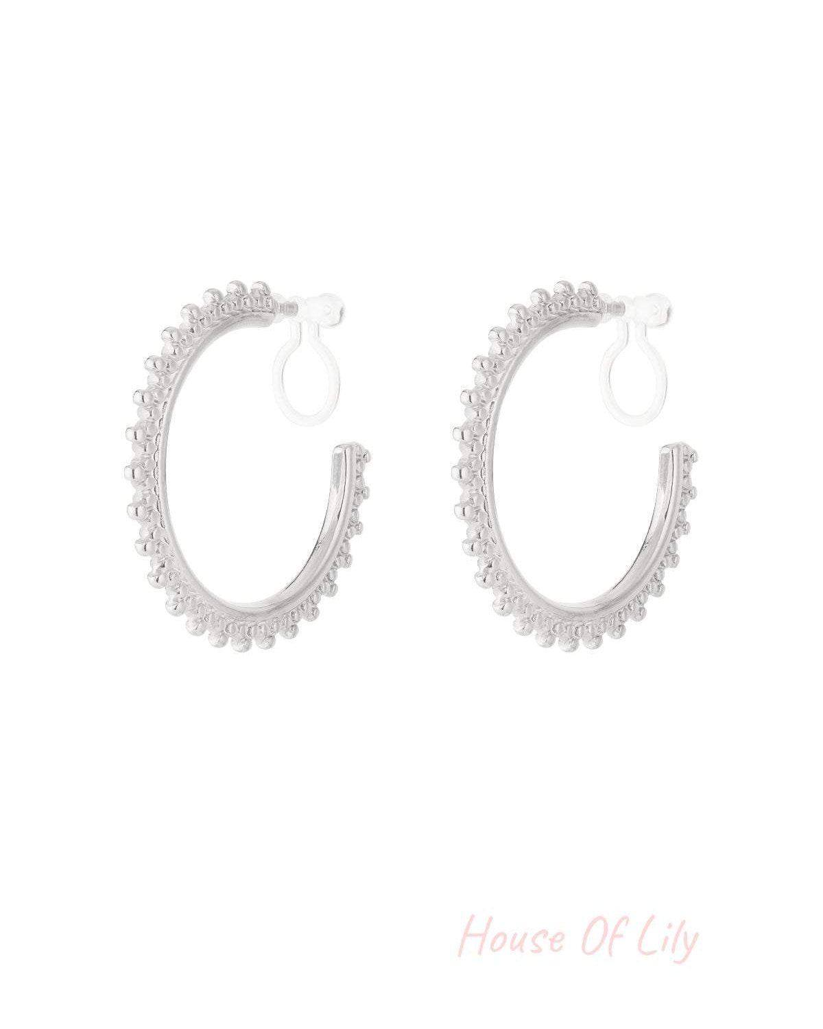 Pair of silver beaded edge clip-on hoop earrings on a white background
