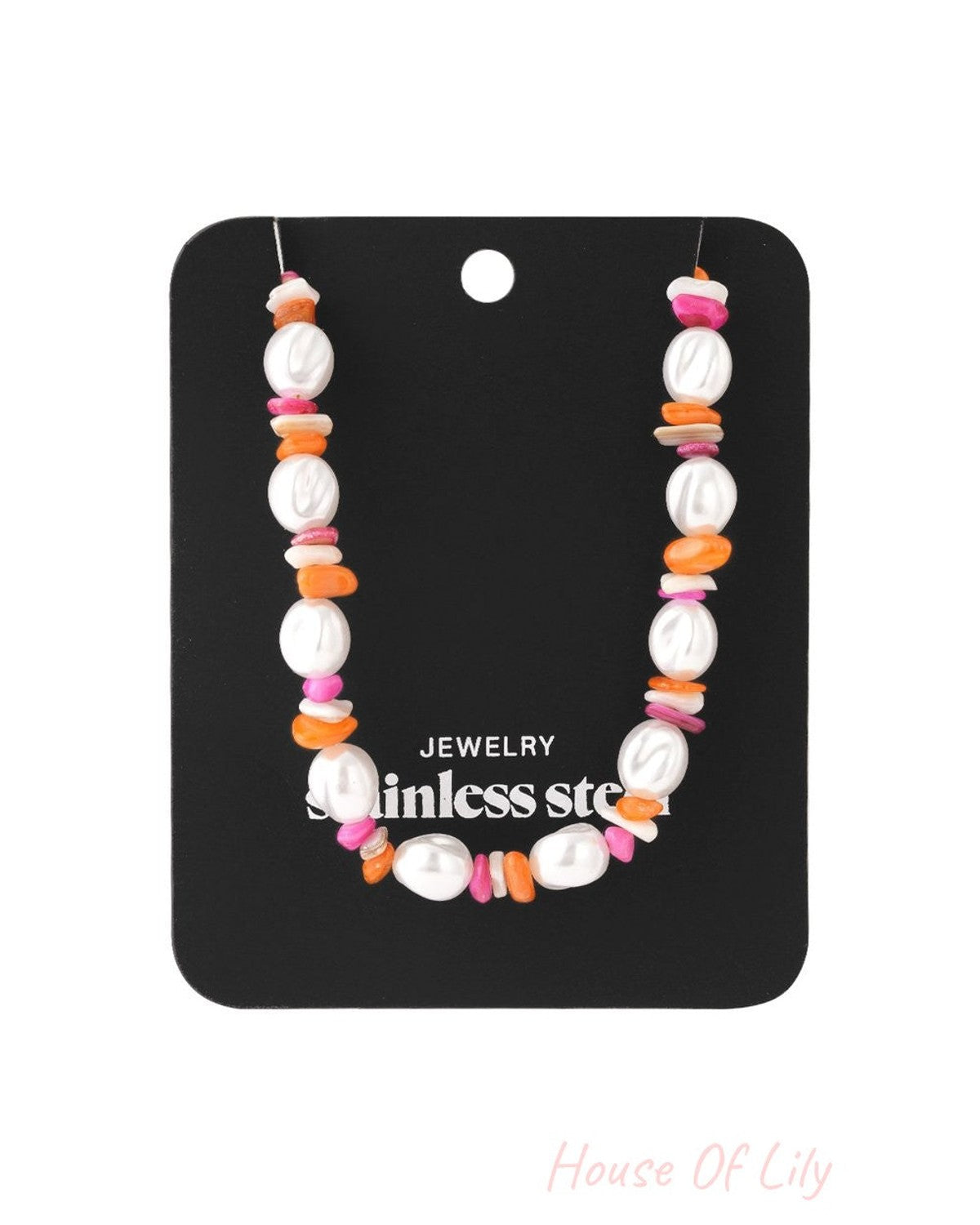 Necklace featuring white baroque pearls interspersed with small, colorful pink and orange chip beads on a display card.