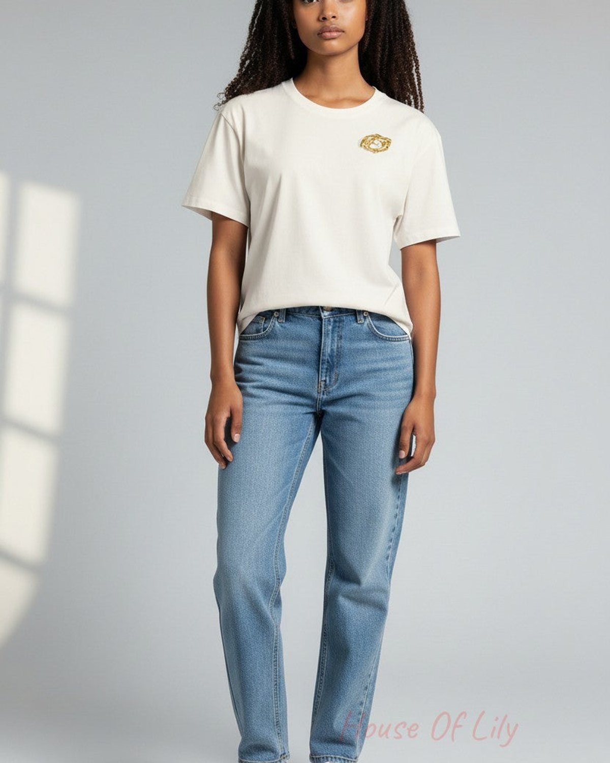 Model wearing a white t-shirt with a Golden Spiral Brooch, an intricate, round gold-toned abstract accessory.