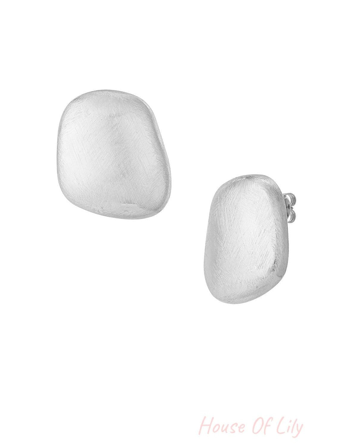 Pair of organic pebble-shaped stud earrings in brushed silver finish on white background