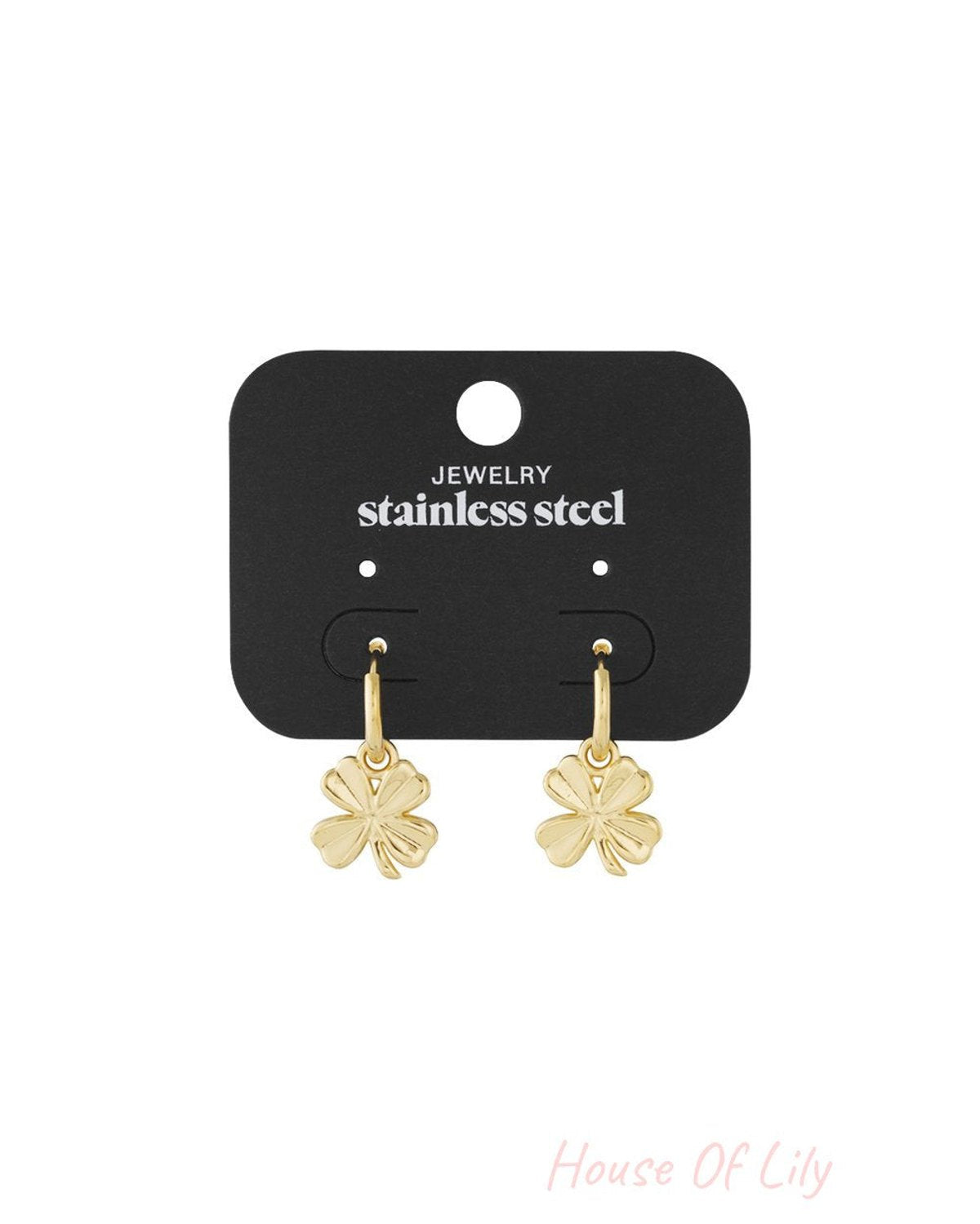 Gold-tone stainless steel hoop earrings featuring dangling four-leaf clover charms on a black display card.