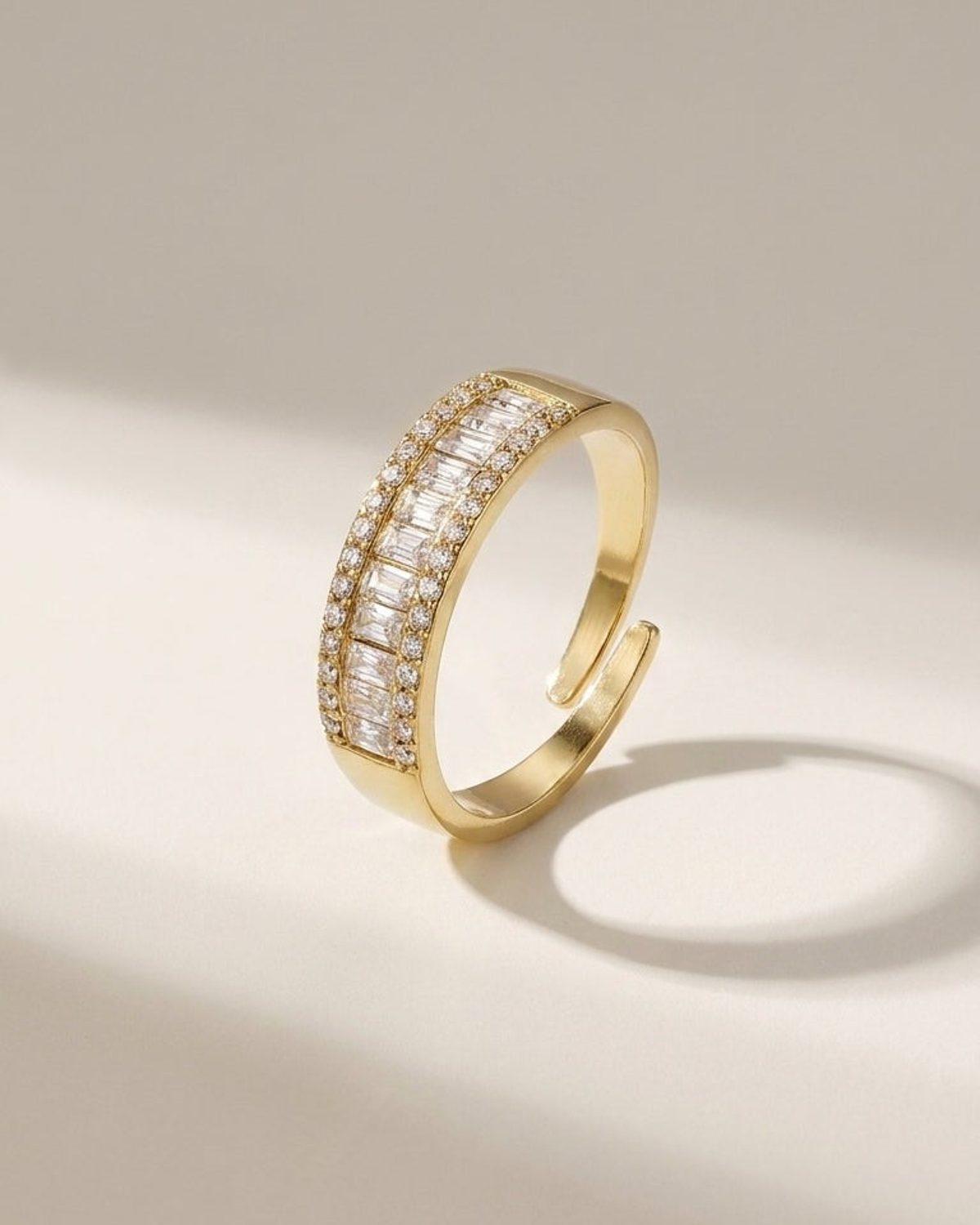 Gold open ring with a center row of baguette stones bordered by small round crystals.