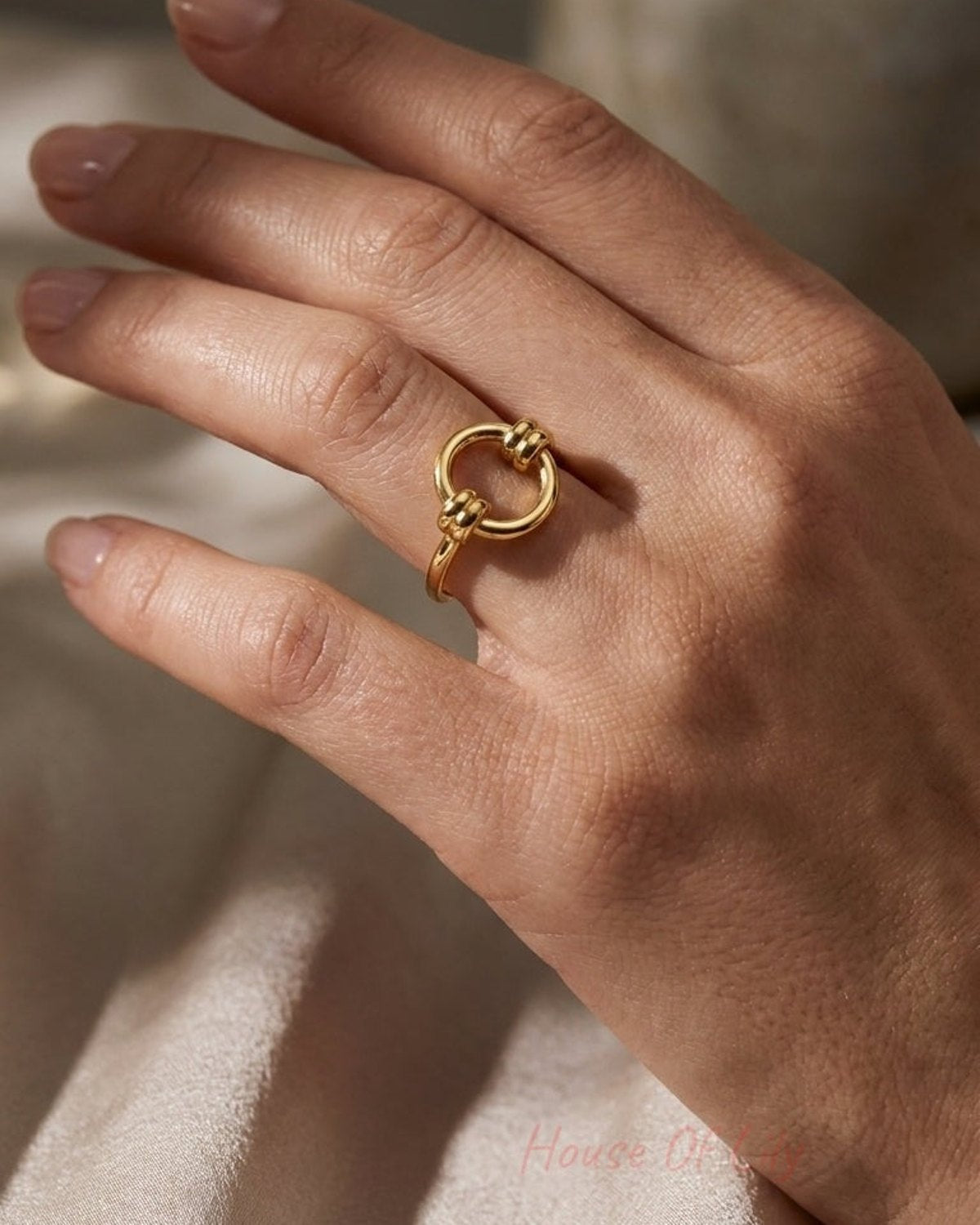 Gold ring featuring a smooth circular band with two small knotted accents.