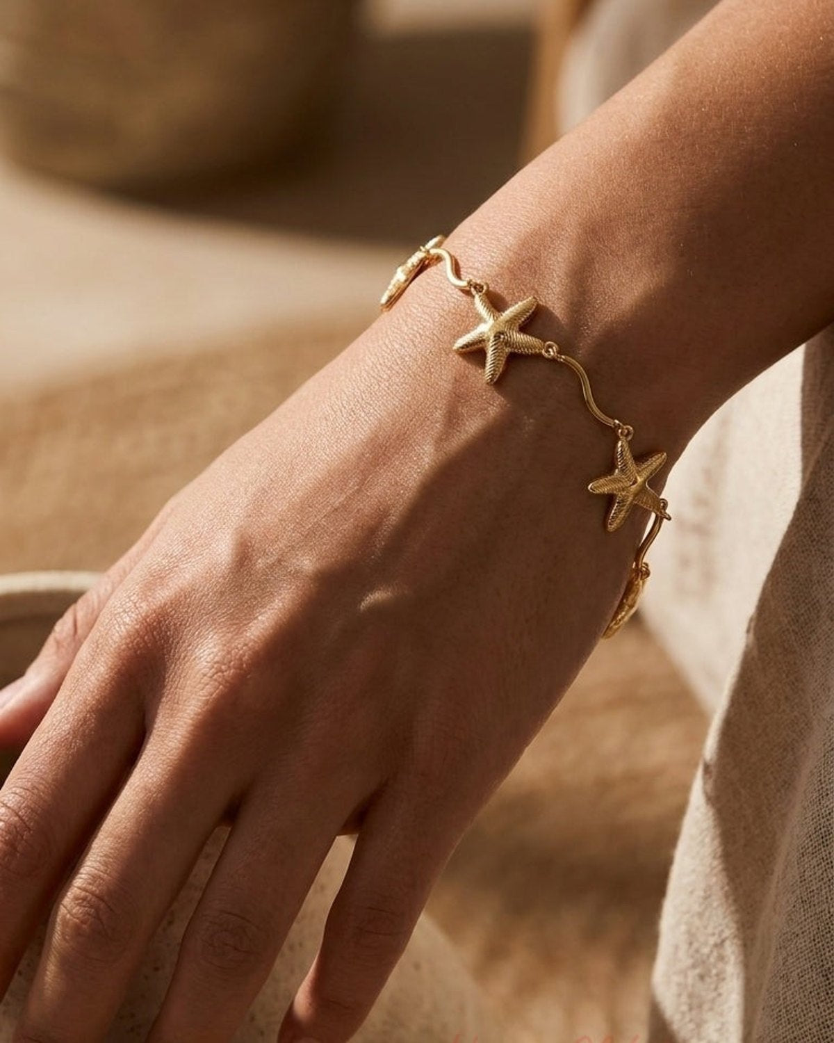 A gold starfish bracelet worn on a person's wrist.