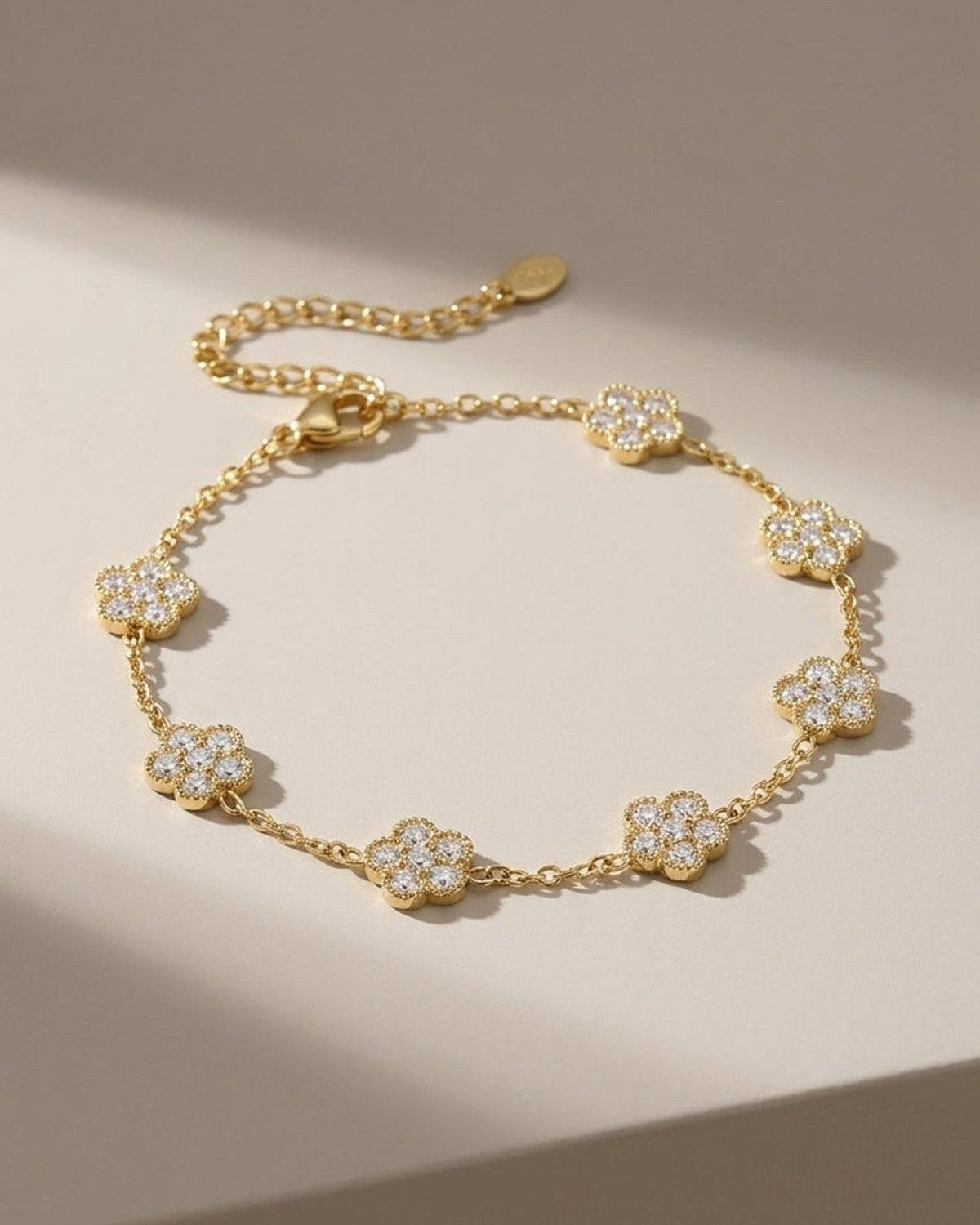 Gold flower charm bracelet featuring crystal-pave flower stations along a delicate link chain.