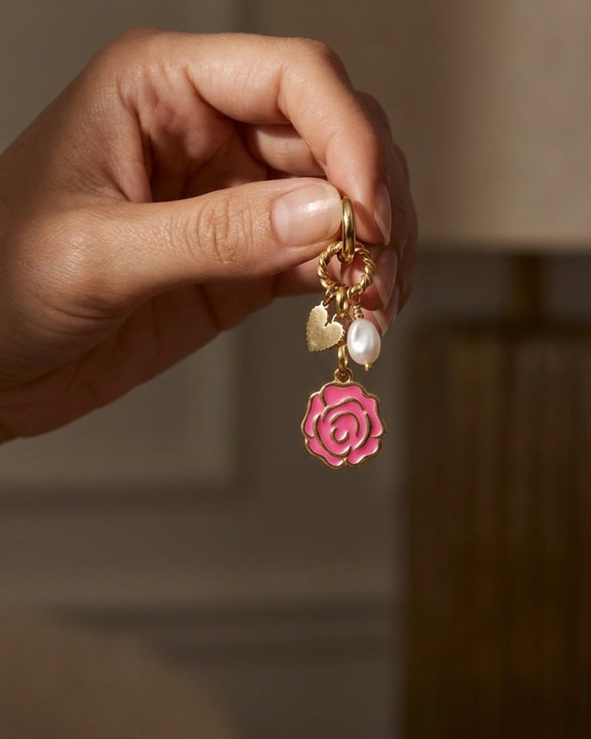 Golden Rose Bloom drop earring with a pink rose charm, heart charm, and pearl on gold-plated metal.