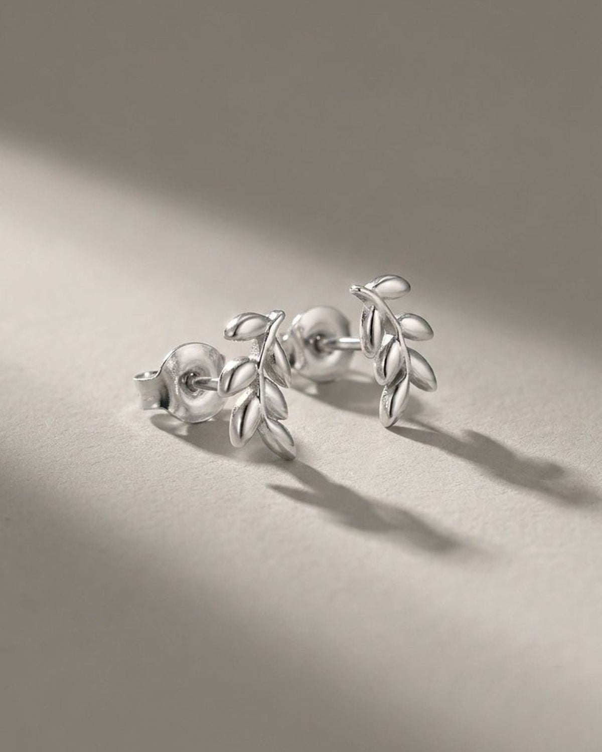 Sprout Vibe Gold earrings: polished gold-tone metal stud earrings shaped like delicate leaf sprigs.
