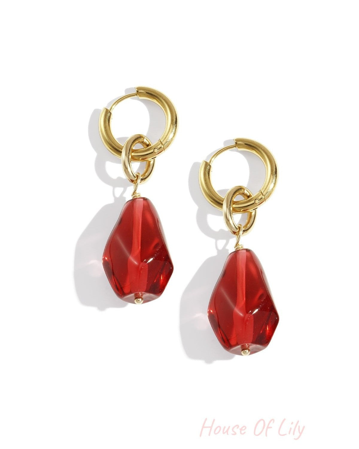Pair of gold hoop drop earrings with irregular crimson red acrylic charms on white background