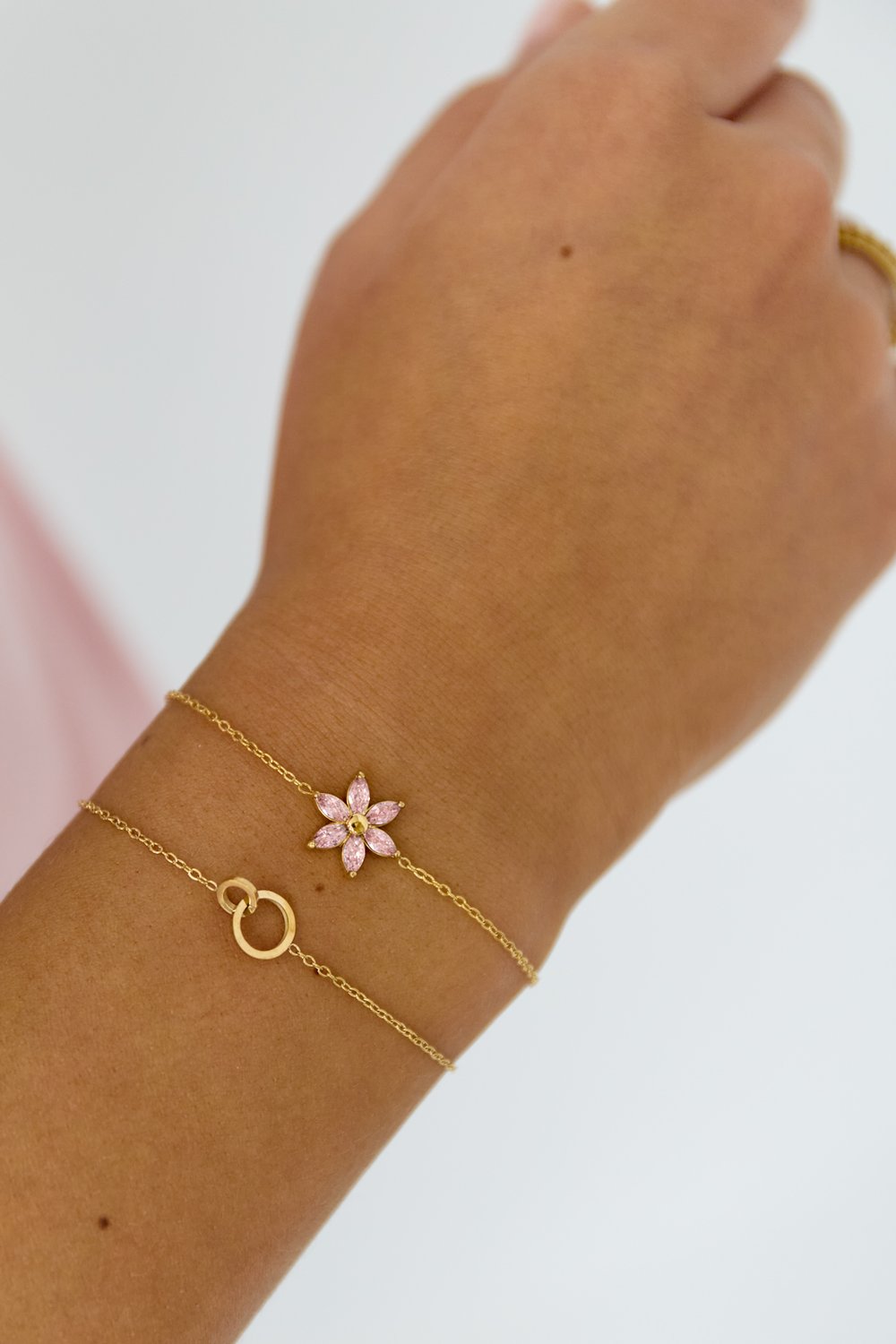 Linked Up: Two delicate gold chain bracelets, one with a pink marquis-cut stone flower and one with interlocked rings.