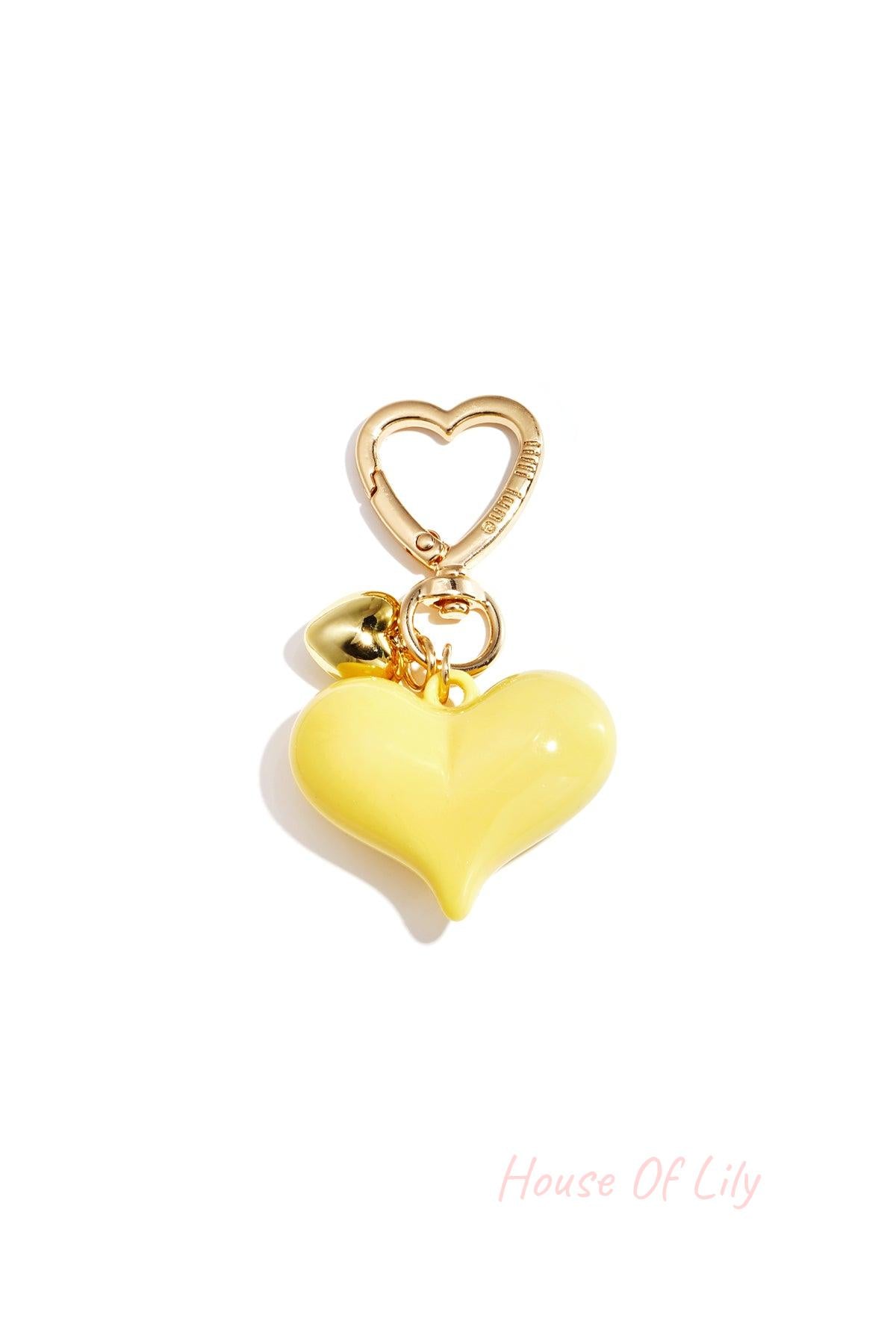 Single yellow acrylic heart bag charm with gold heart clasp and mini gold heart pendant on white background