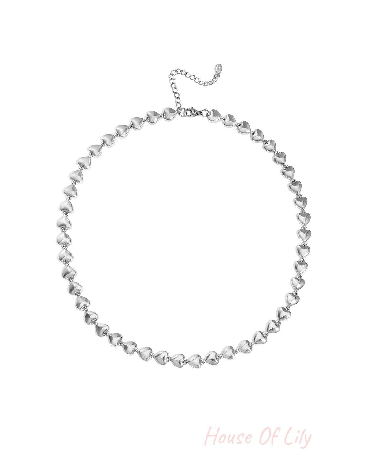 Silver heart-shaped link chain necklace laid flat with adjustable clasp on white background