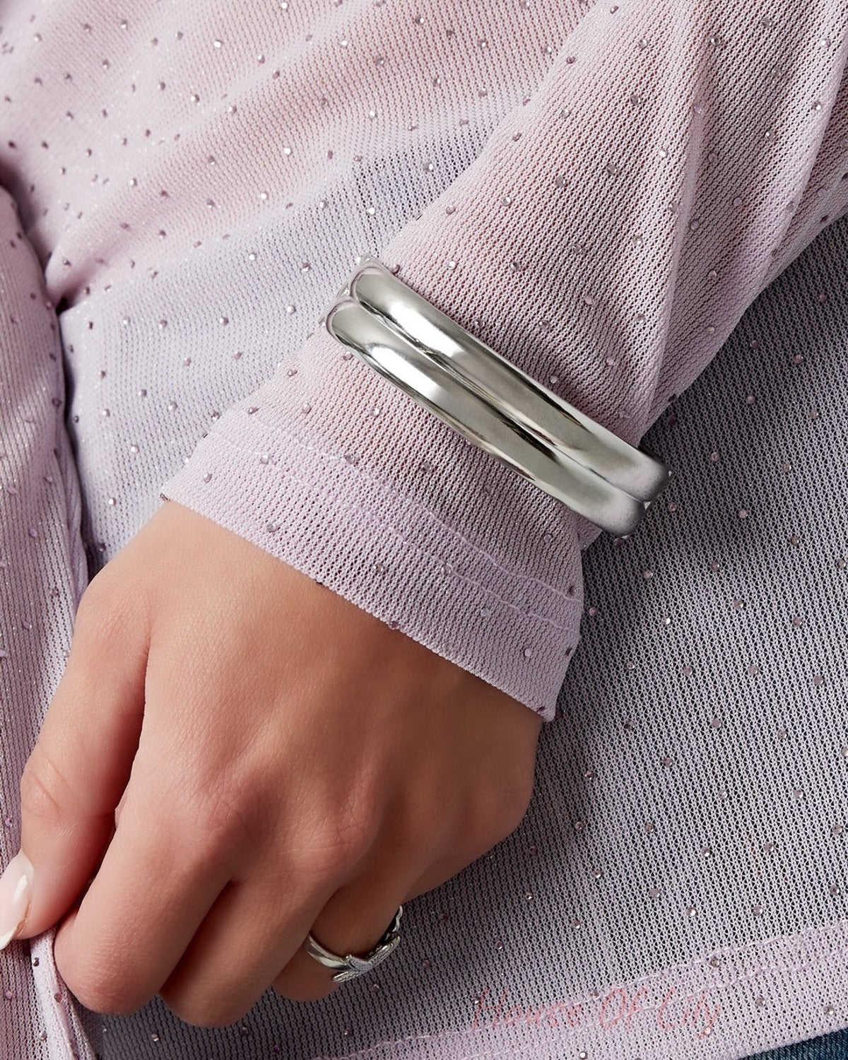 Silver double-band bangle worn on wrist, styled with a delicate purple sheer sleeve and silver ring, highlighting youthful aesthetic