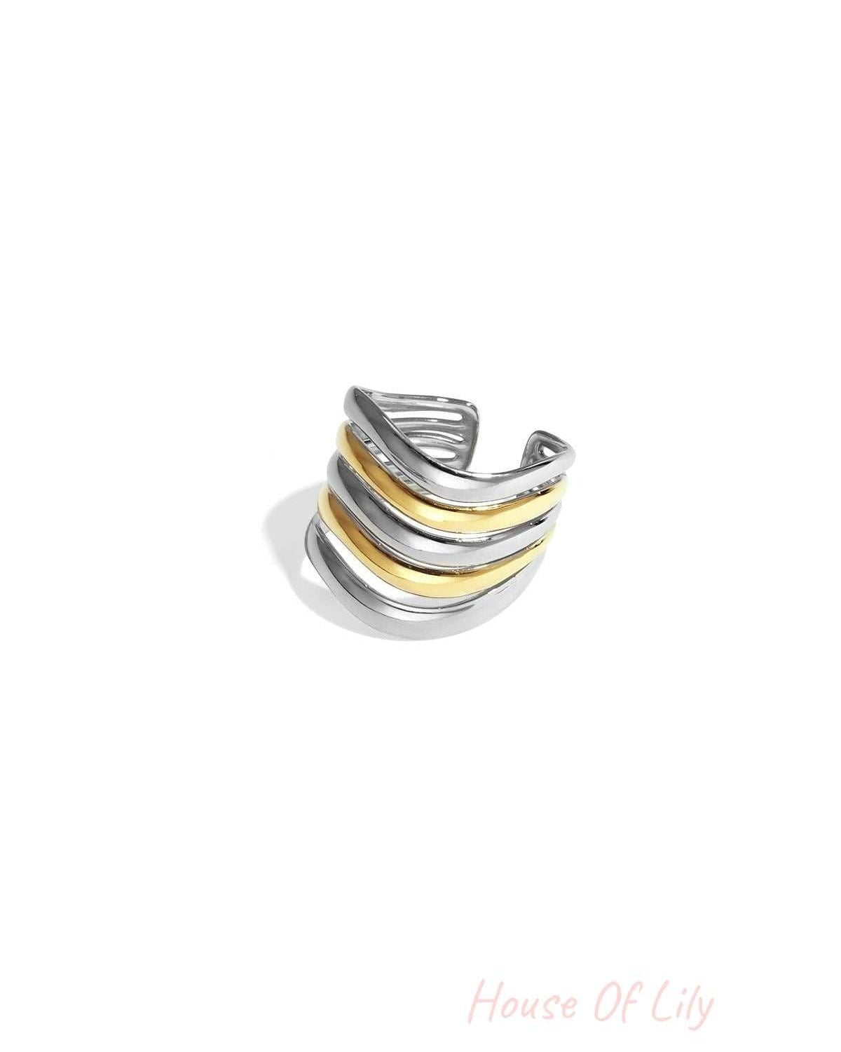 Close-up of a bi-color gold and silver wavy layered statement ring with five curved bands on a white background