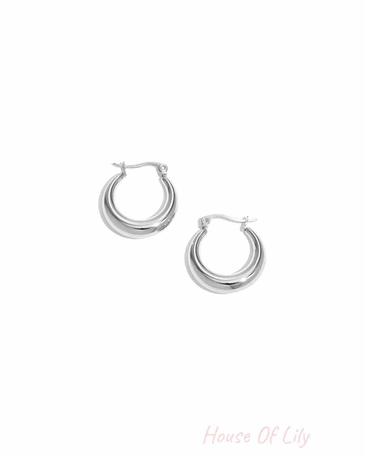 Pair of shiny chunky silver hoop earrings with a smooth polished finish displayed on a white background