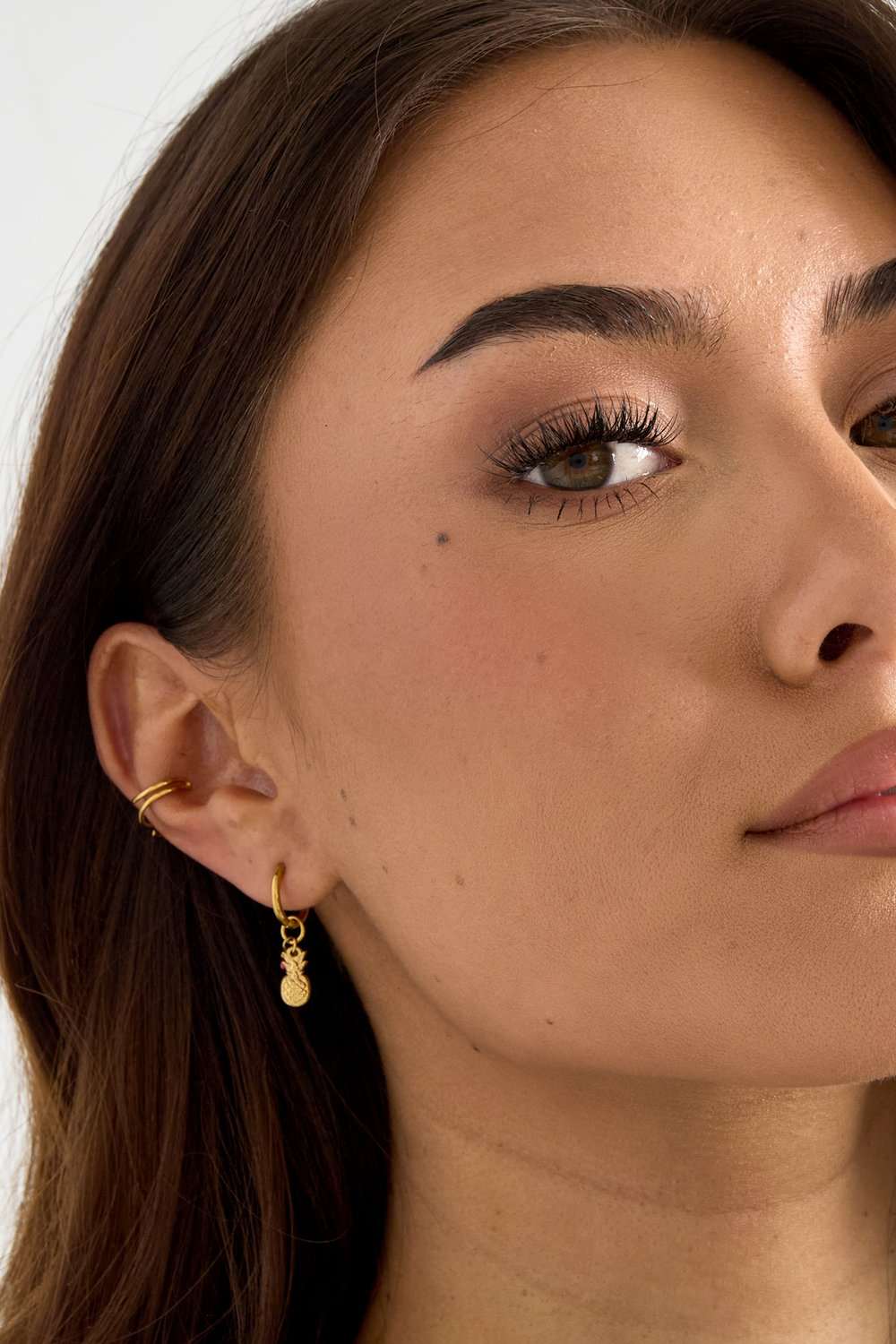 Model wearing Pineapple Aura Drops: a small gold hoop earring with a dangling textured pineapple charm.