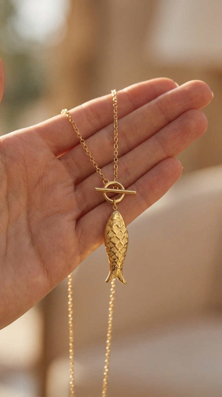 Gold Catching Vibes necklace featuring a textured fish pendant on a delicate chain with a toggle clasp.