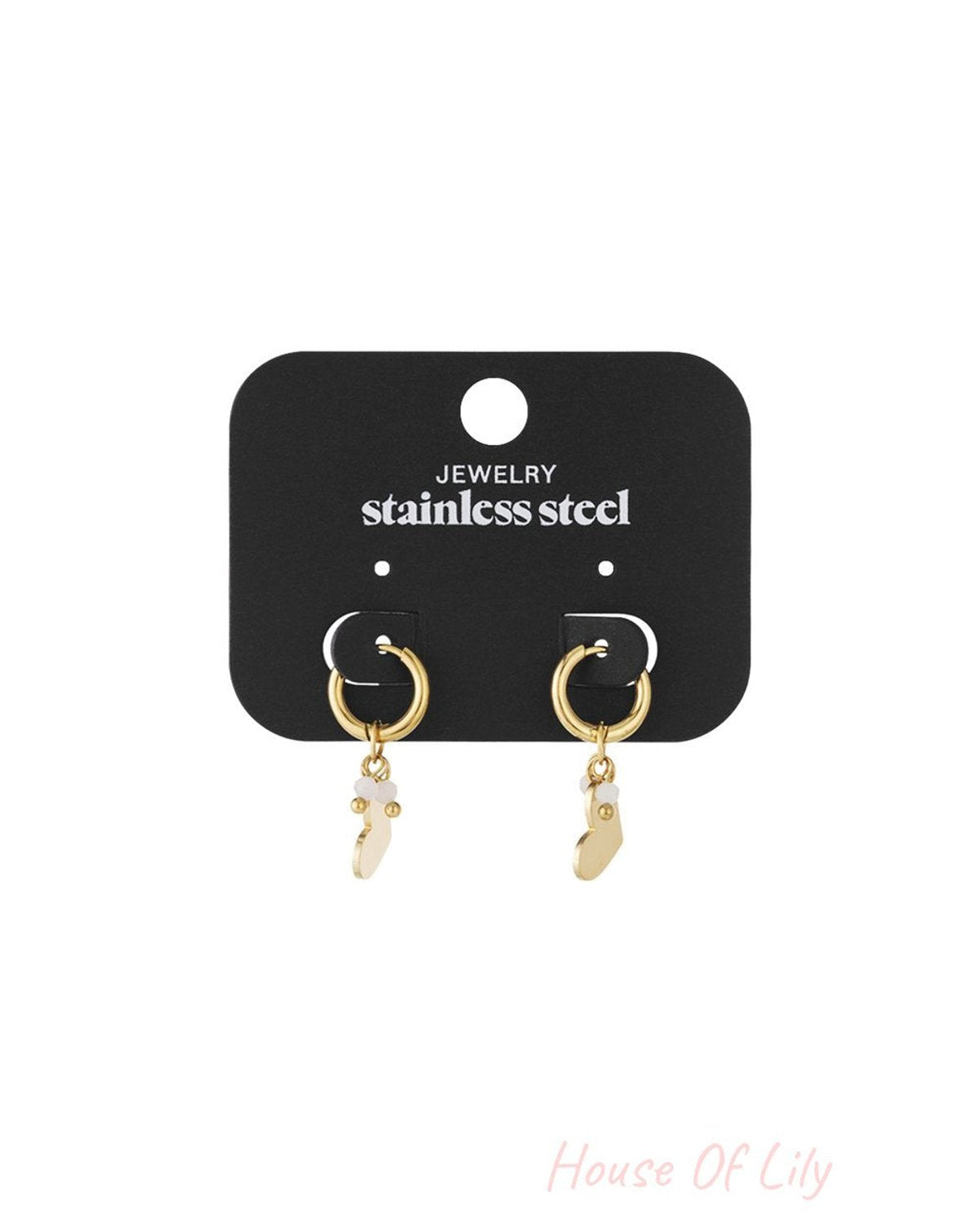 Gold-tone stainless steel hoop earrings featuring dangling heart charms with small white accents on a display card.