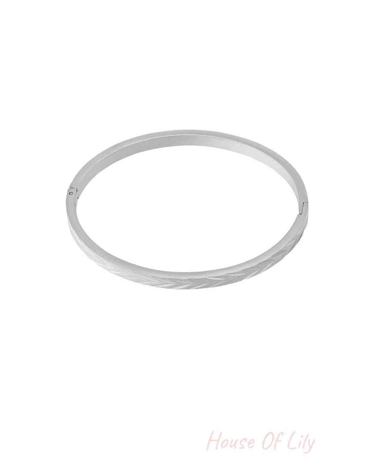 Silver-tone stainless steel bangle bracelet with embossed herringbone pattern on white background