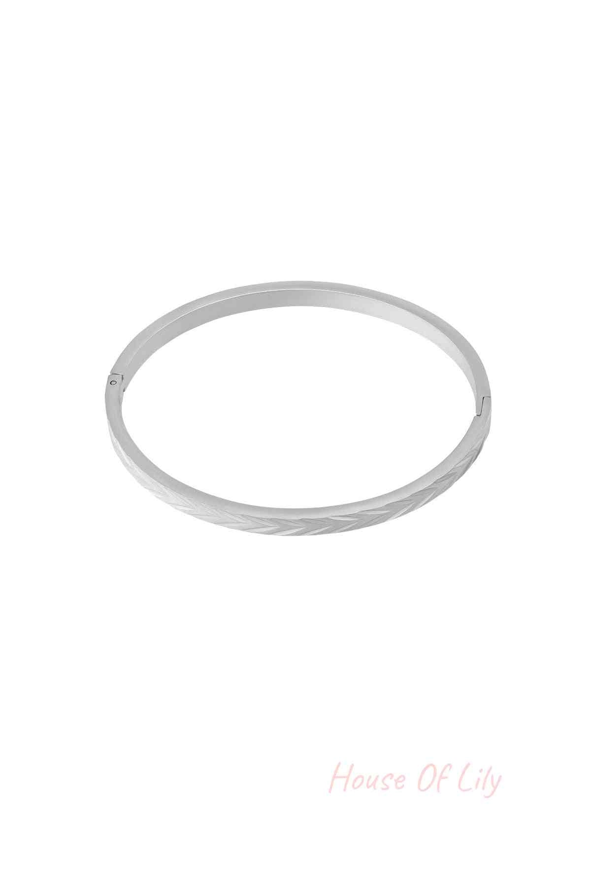 Silver-tone stainless steel bangle bracelet with embossed herringbone pattern on white background