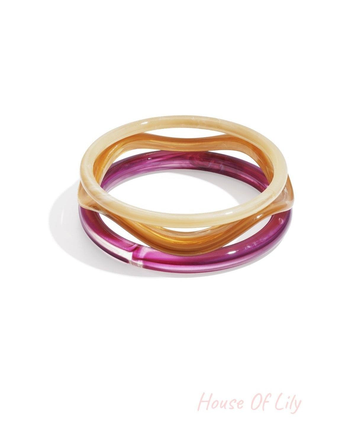 Set of three wavy acrylic bangles in translucent cream, amber, and deep magenta with a smooth, glossy finish.
