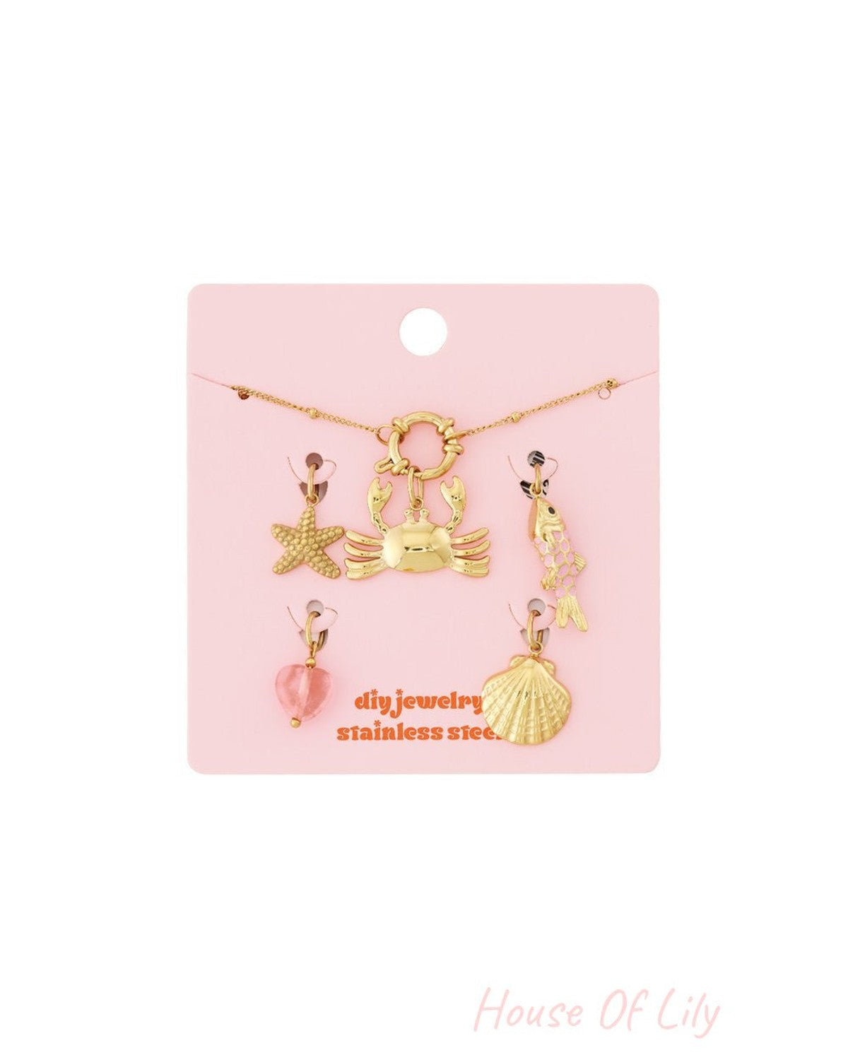 Gold stainless steel charm bracelet kit with crab, starfish, fish, shell, and heart charms on a pink display card.