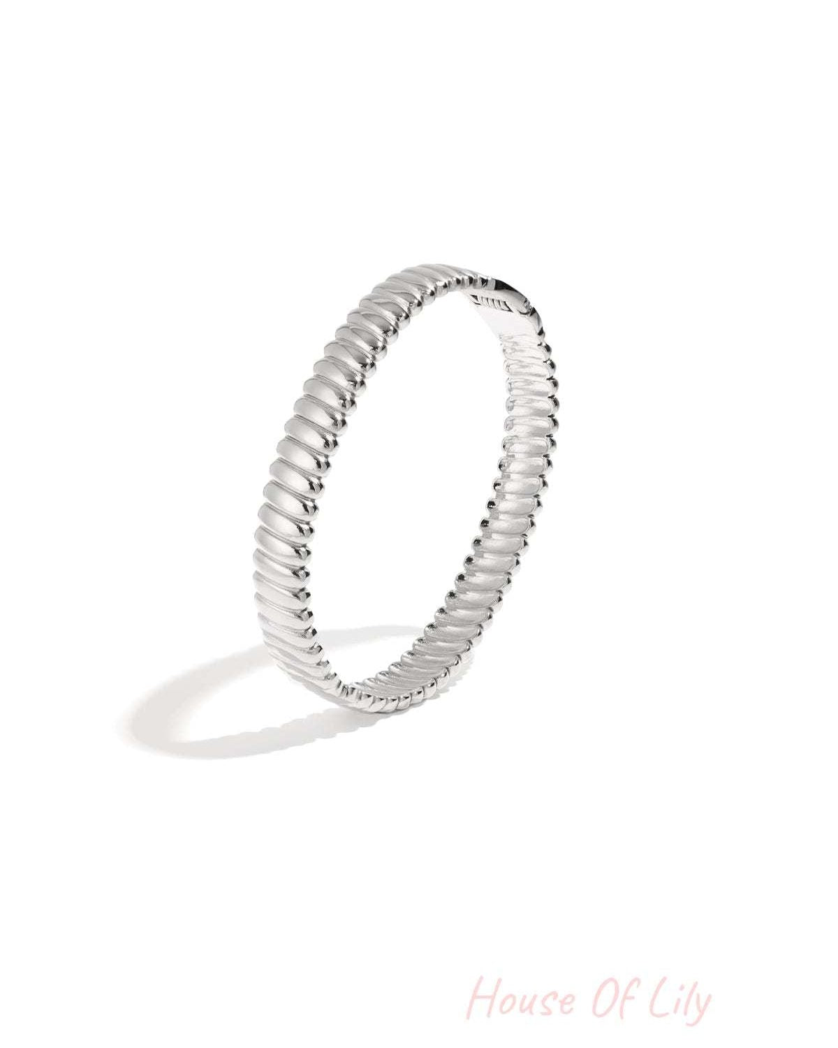Close up of silver textured ribbed bangle jewelry on white background