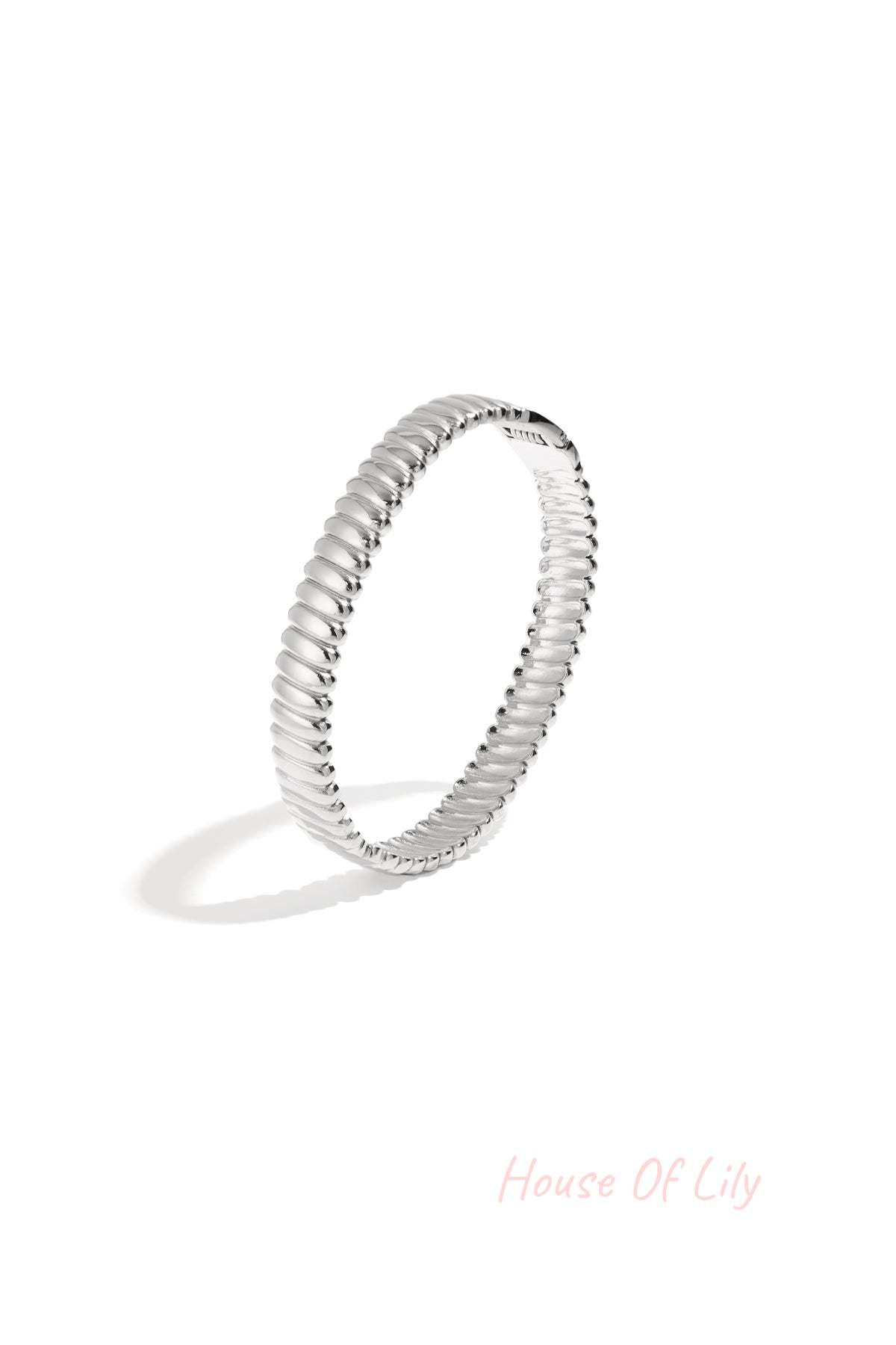 Close up of silver textured ribbed bangle jewelry on white background