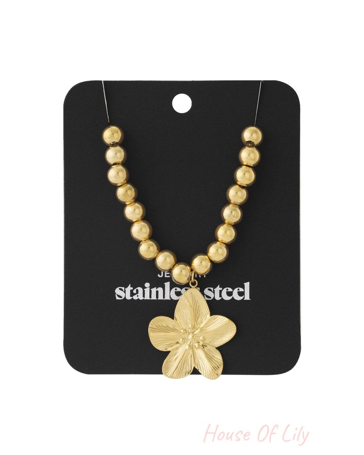 Gold-tone stainless steel necklace with round hollow beads and a textured, five-petal flower pendant on a display card.