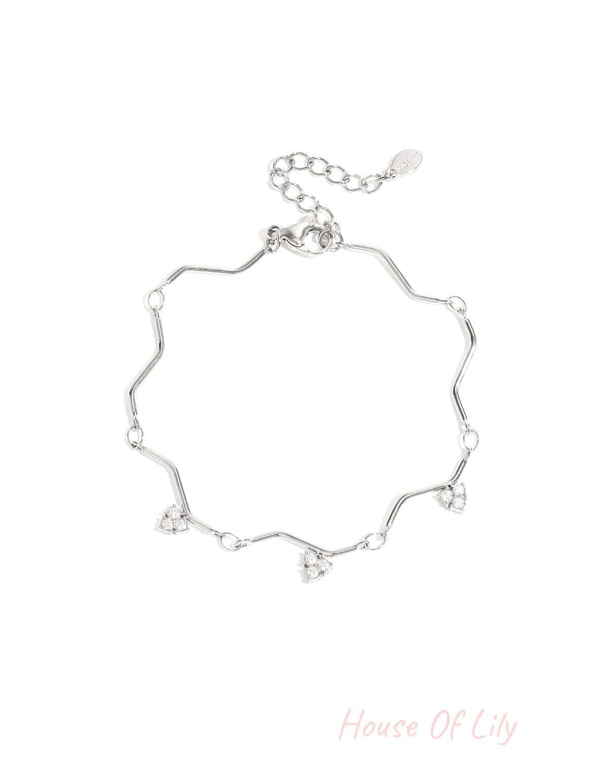 Silver zigzag charm bracelet with heart-shaped rhinestone charms displayed on white background