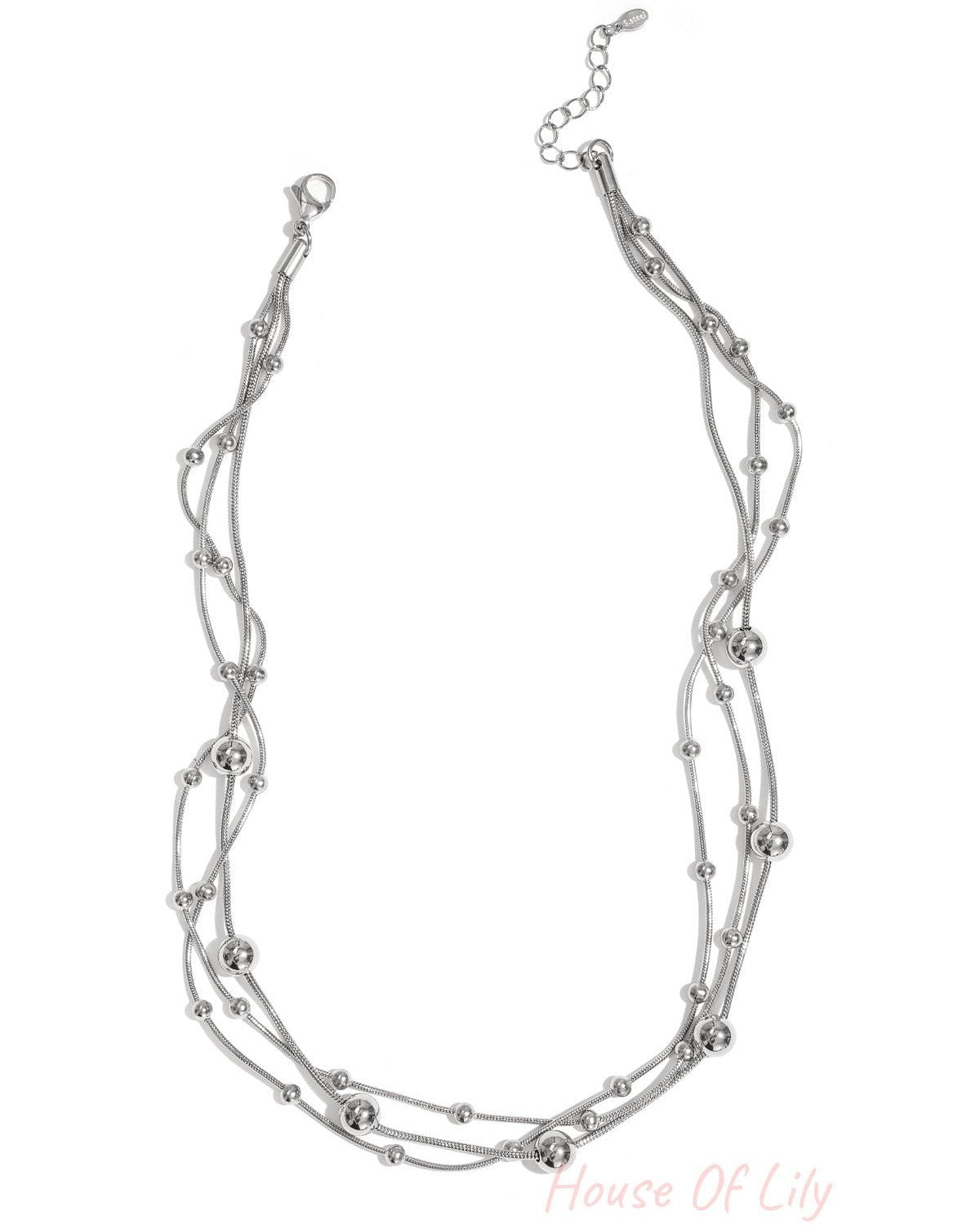Silver multi-layered necklace with small and large beads laid flat on white background