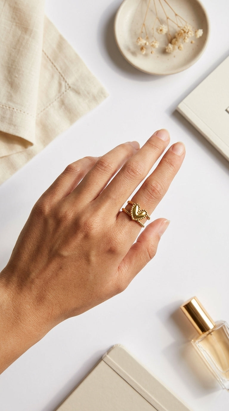 Gold Double Trouble ring featuring a heart design on a beaded band, worn on a hand.