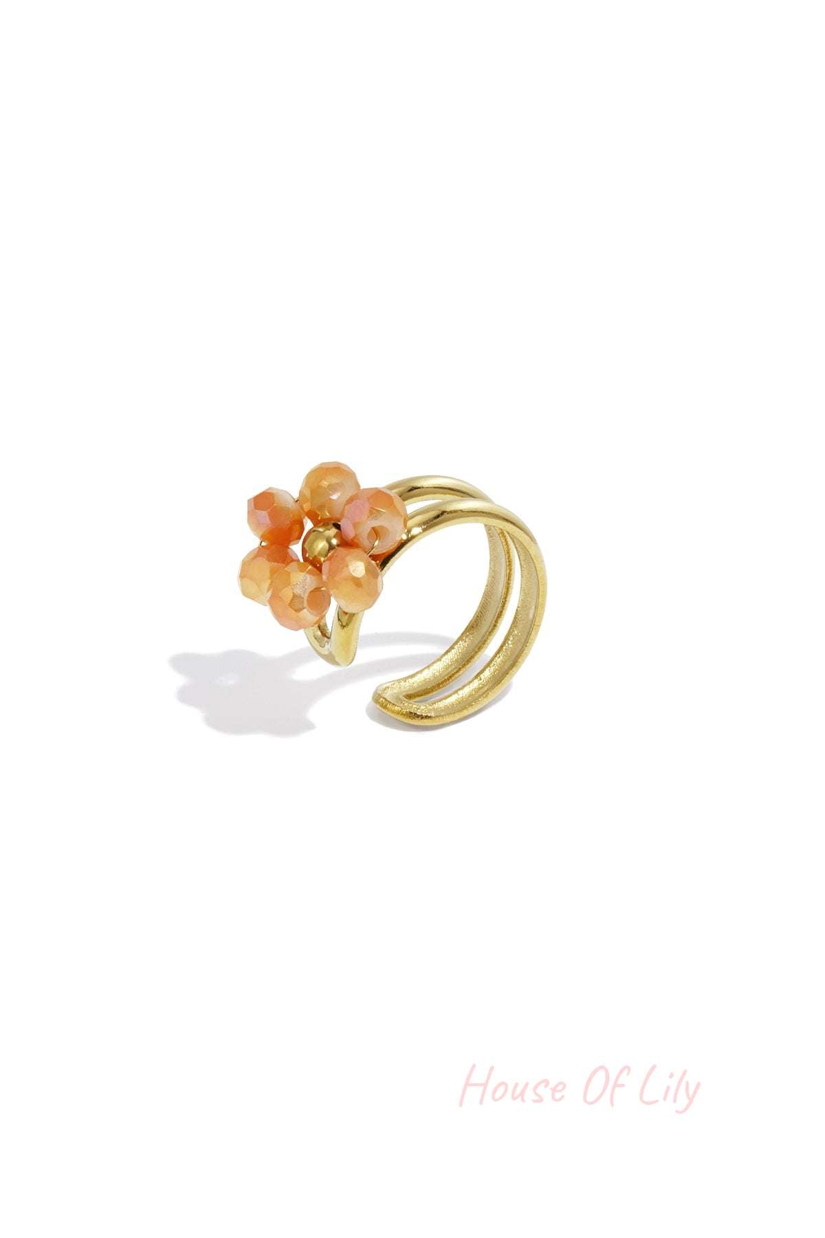 Gold-tone floral ear cuff featuring orange faceted beads on a white background