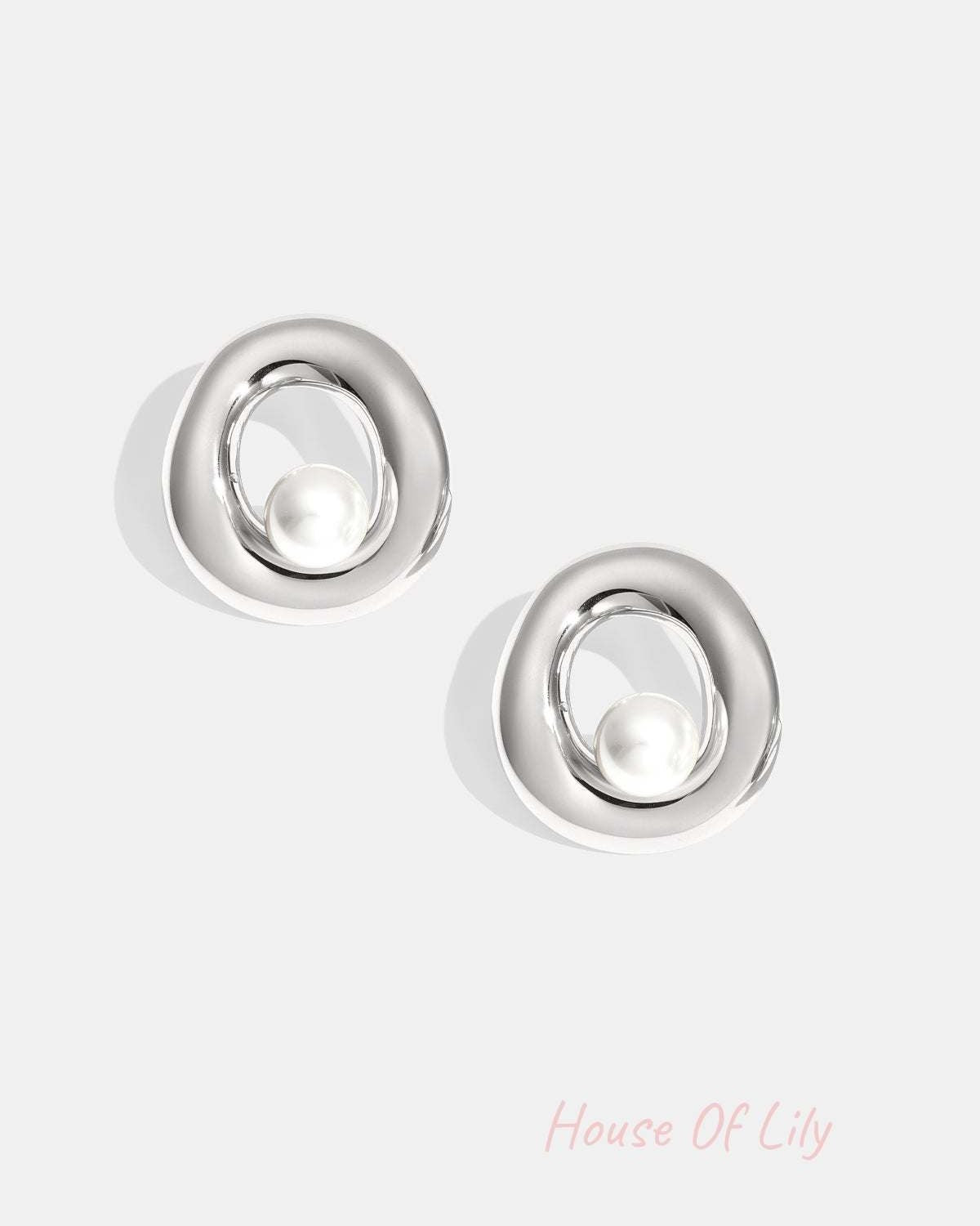 Pair of silver-tone circle stud earrings with pearl centerpiece on white background