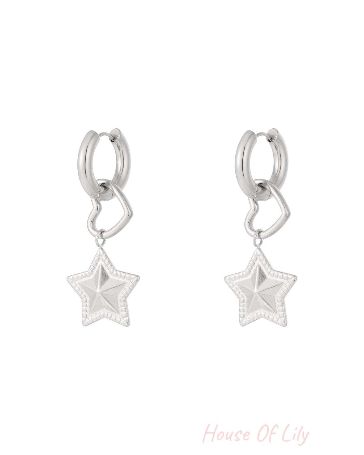Pair of silver hoop earrings with dangling open heart and textured star charms on white background