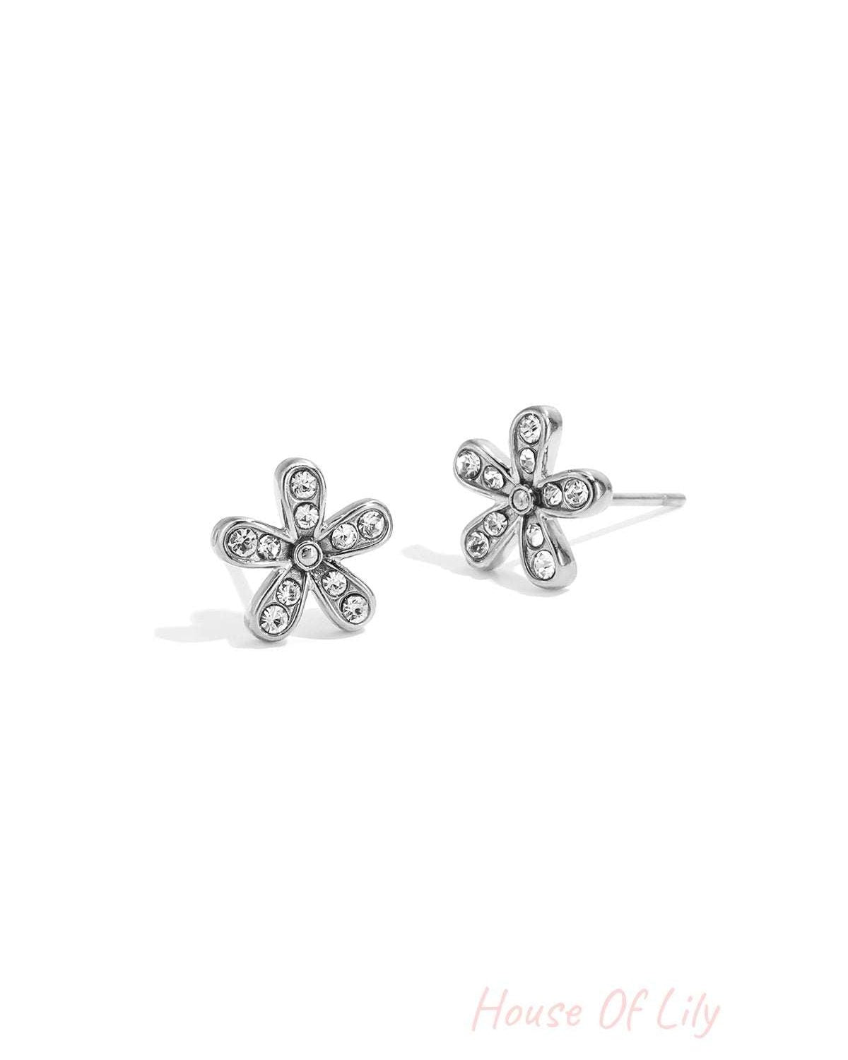 Close-up of silver flower stud earrings with clear rhinestones on each petal, isolated on white background