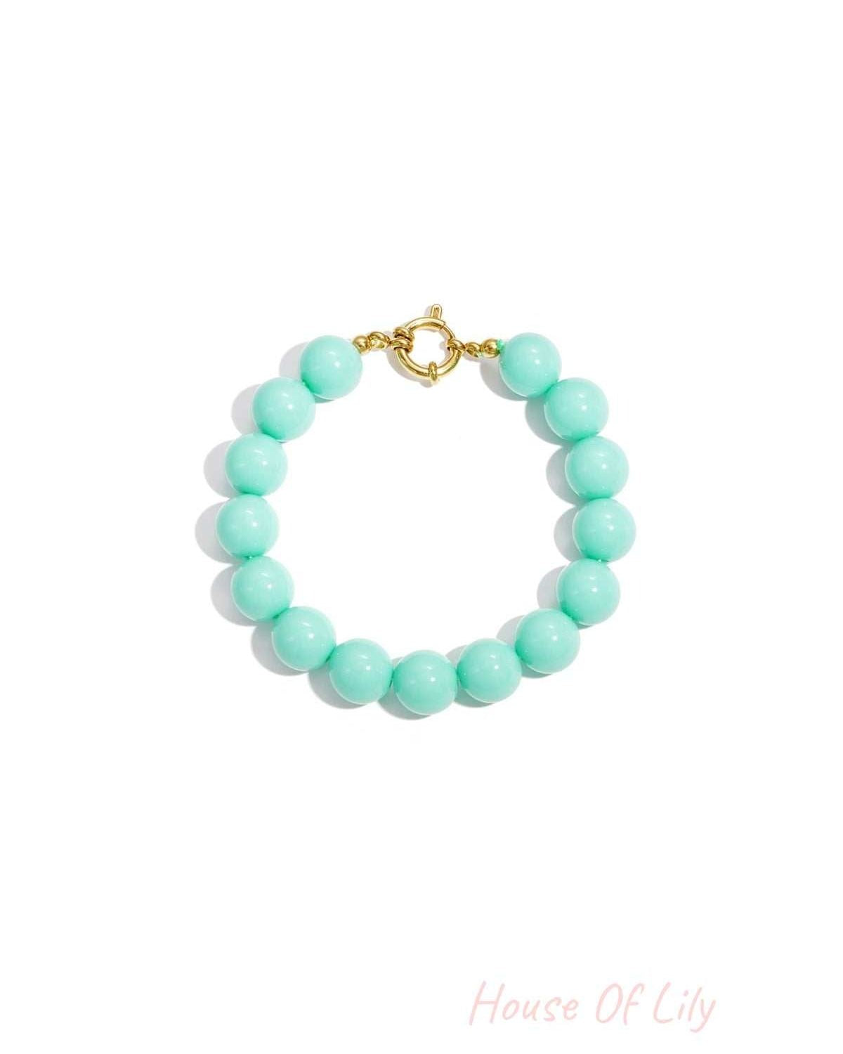 Vibrant teal resin bead bracelet with a gold-tone circular clasp, isolated on a white background.