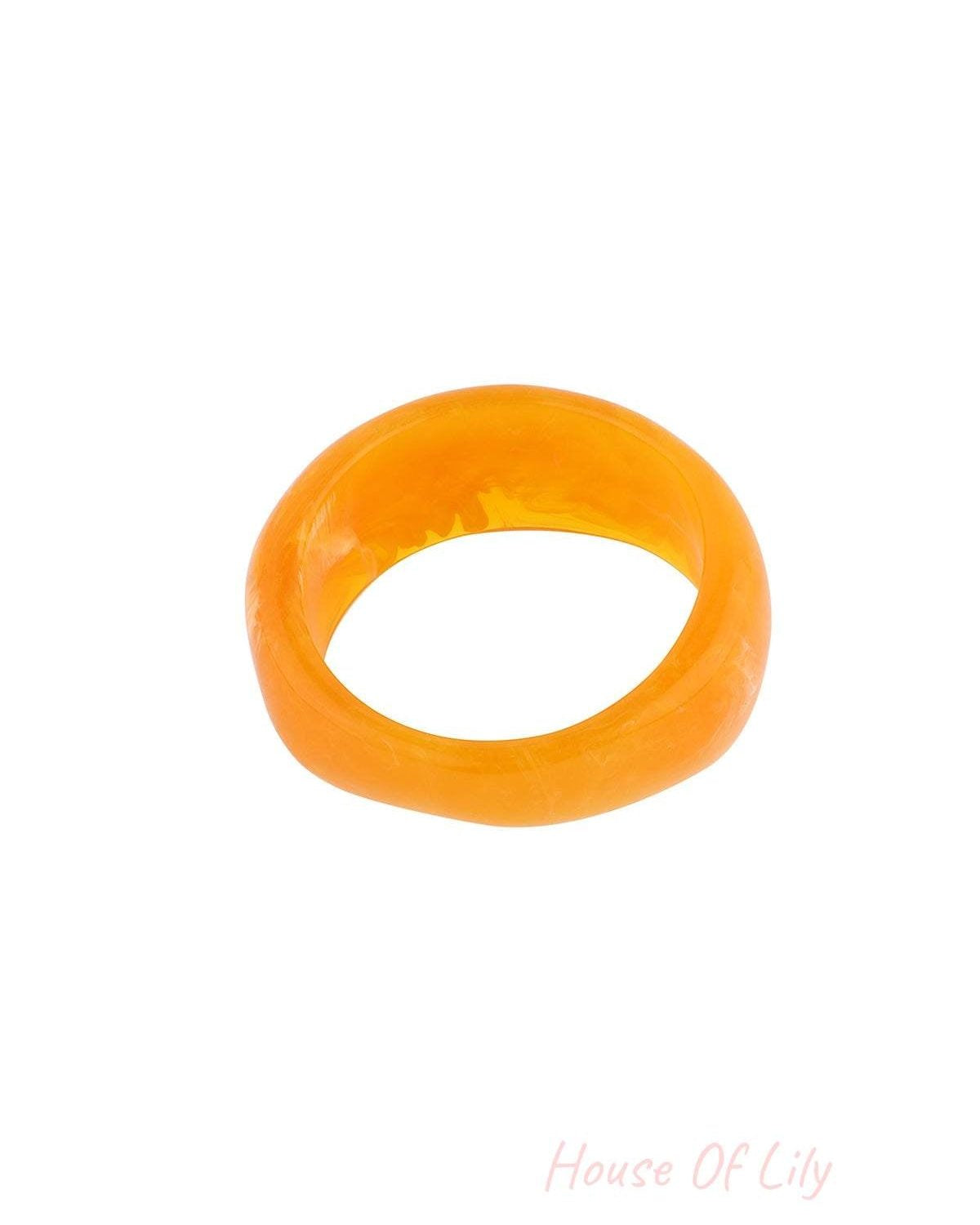 Close-up of bright orange marbled resin bangle bracelet on white background