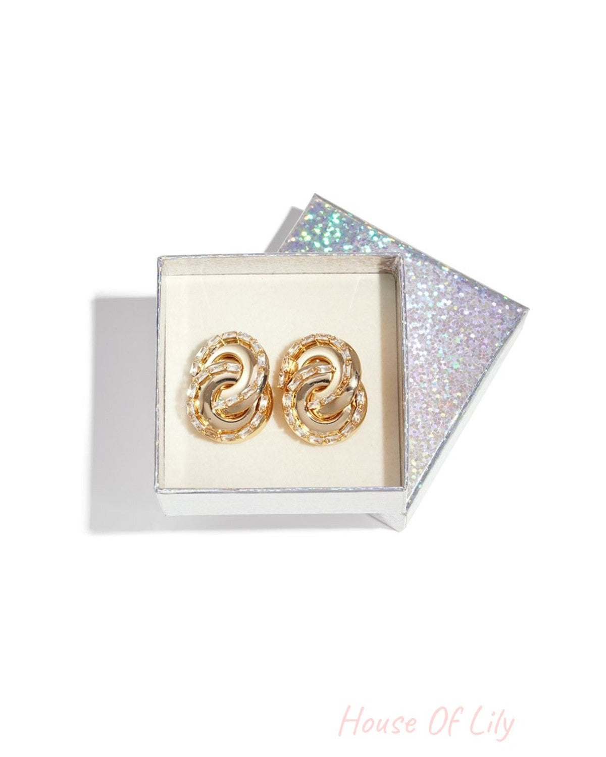 Spiraled Vibe Drops: Gold spiral earrings encrusted with baguette-cut crystals, presented in a glittery gift box.
