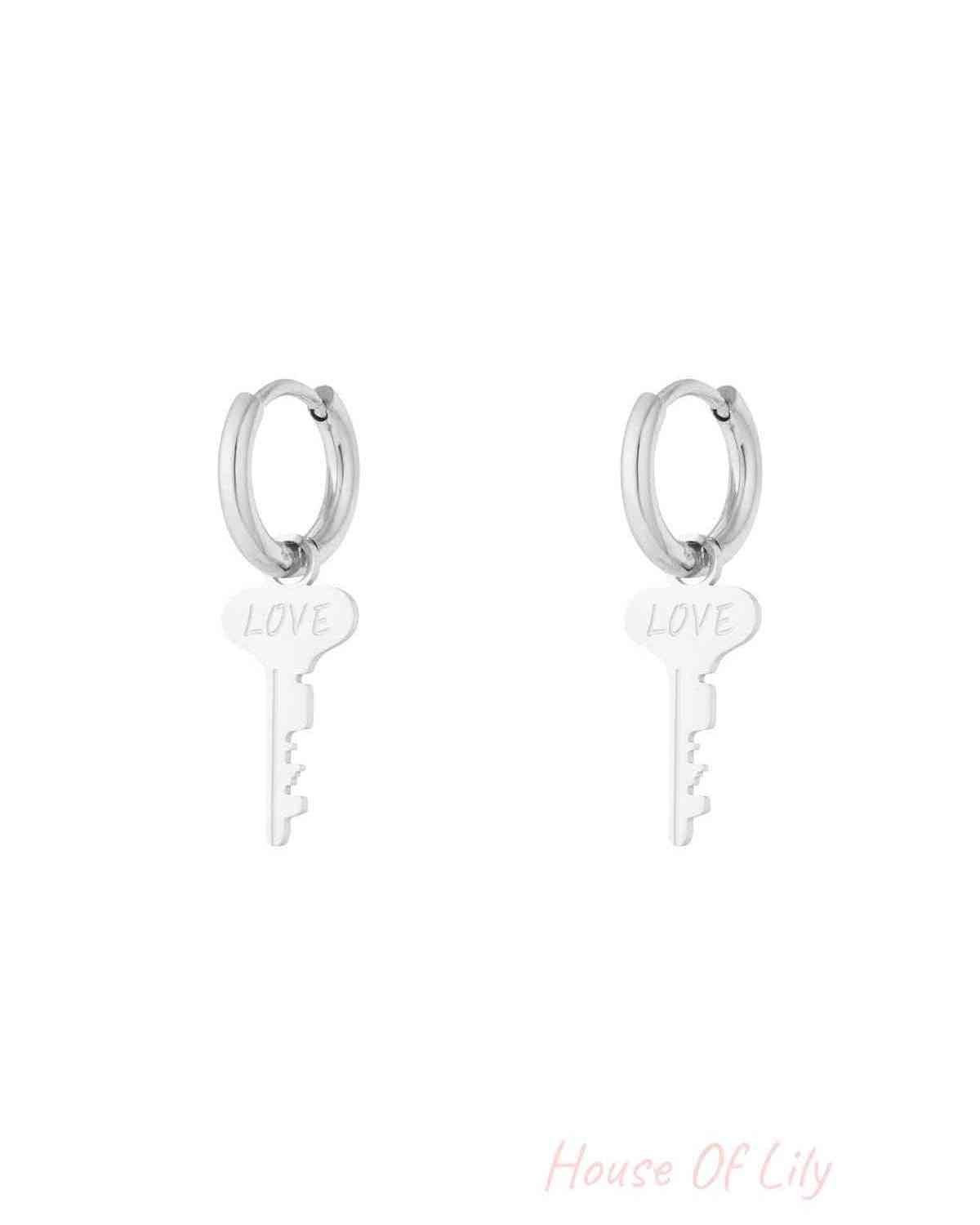 Pair of silver hoop earrings with dangling key-shaped charms engraved with the word 'LOVE' on a white background