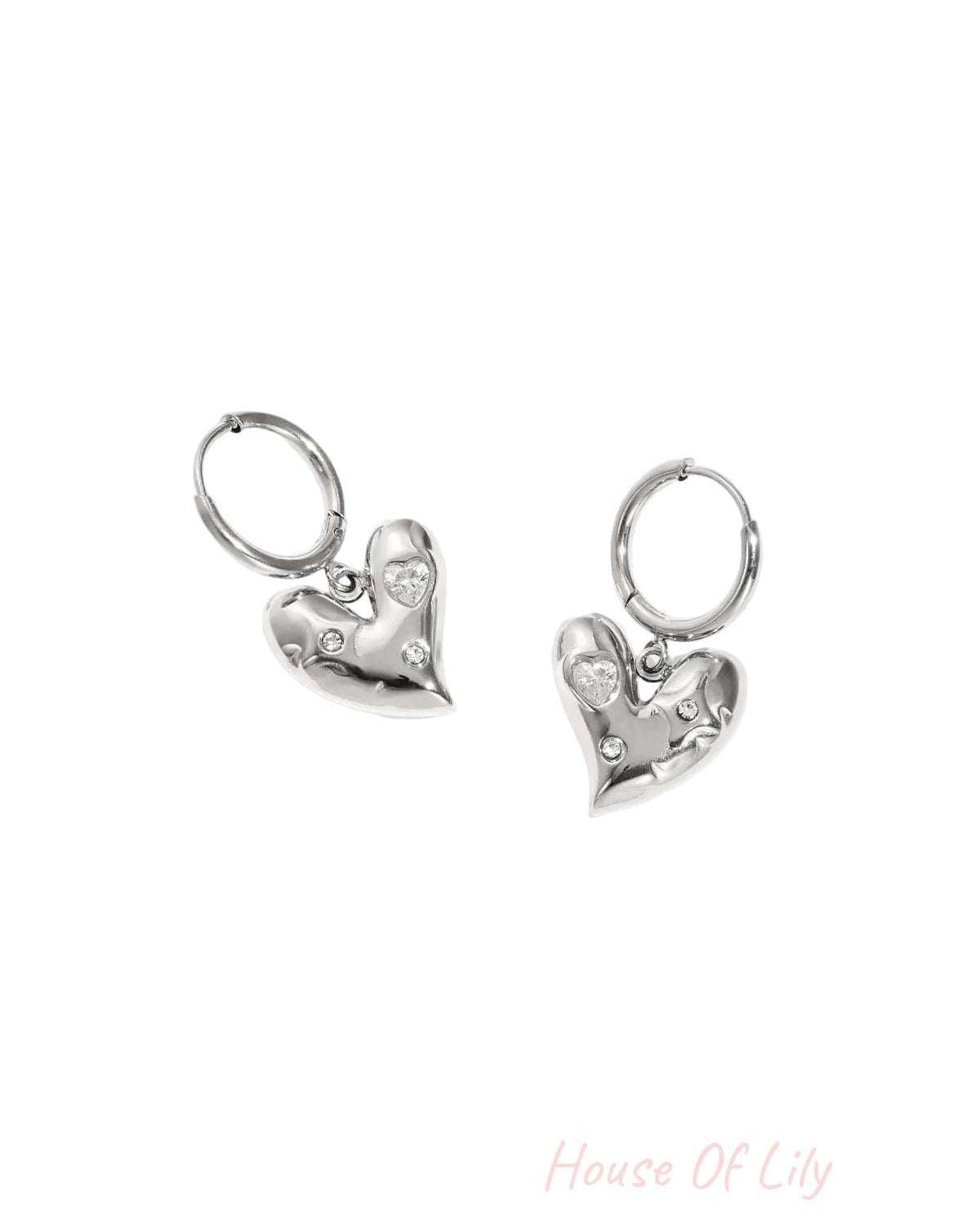 Pair of silver heart charm drop hoop earrings with rhinestone accents on white background