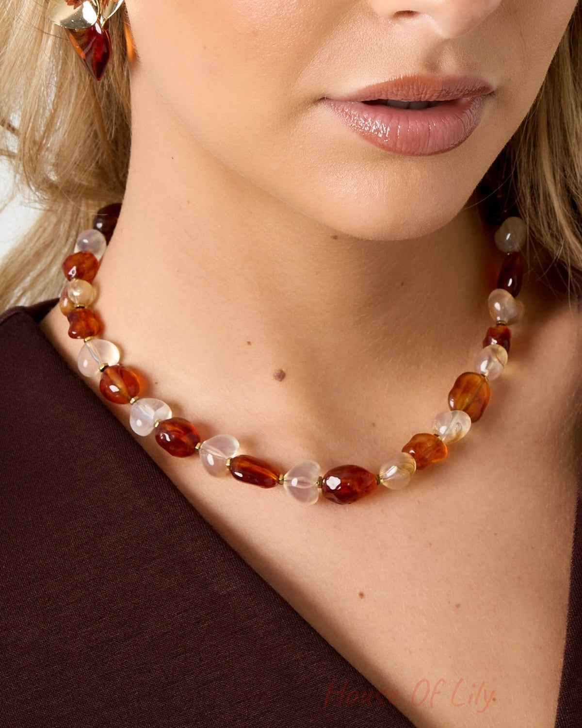 Close-up of model’s neck showing amber and white translucent acrylic beads on necklace