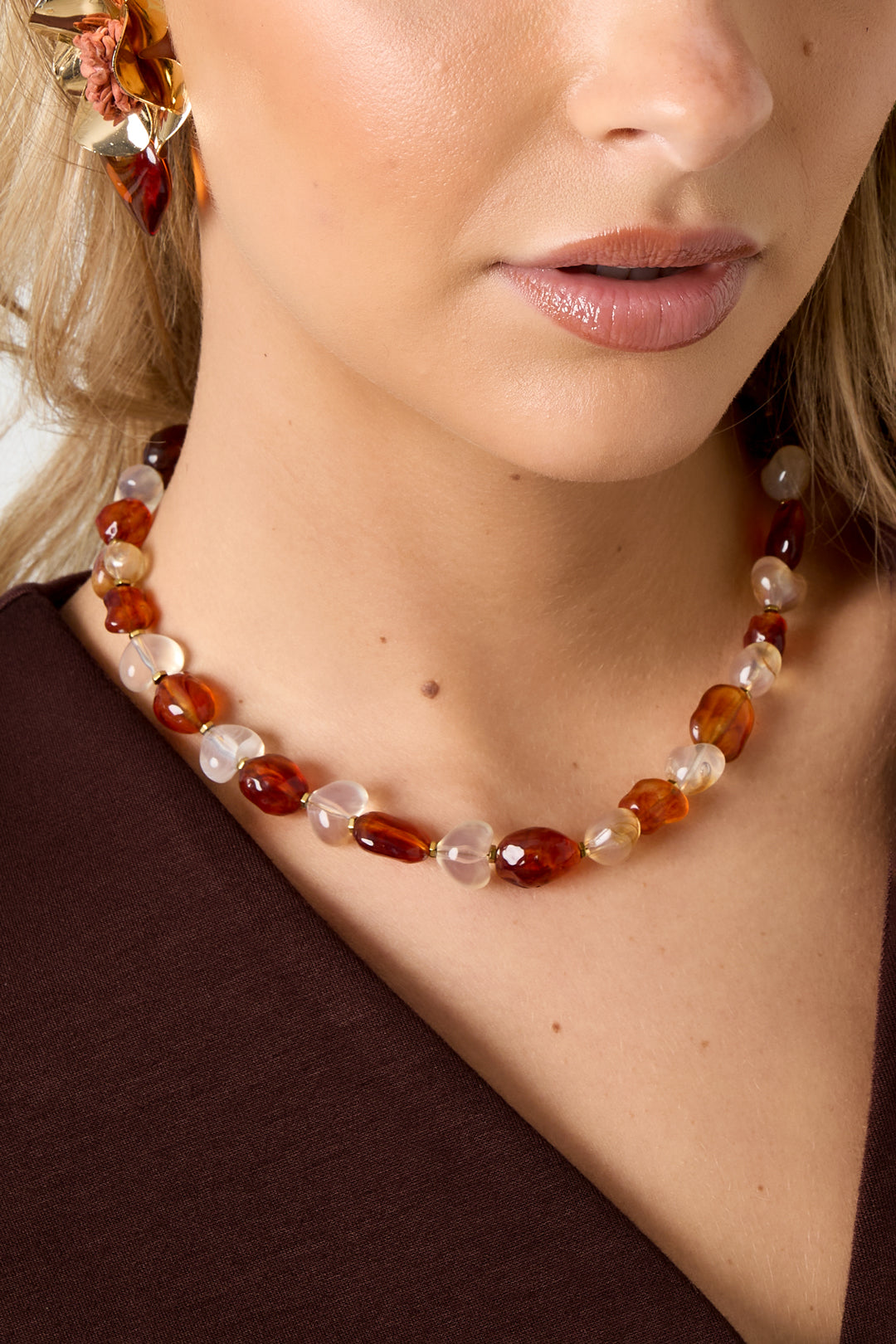 Close-up of model’s neck showing amber and white translucent acrylic beads on necklace