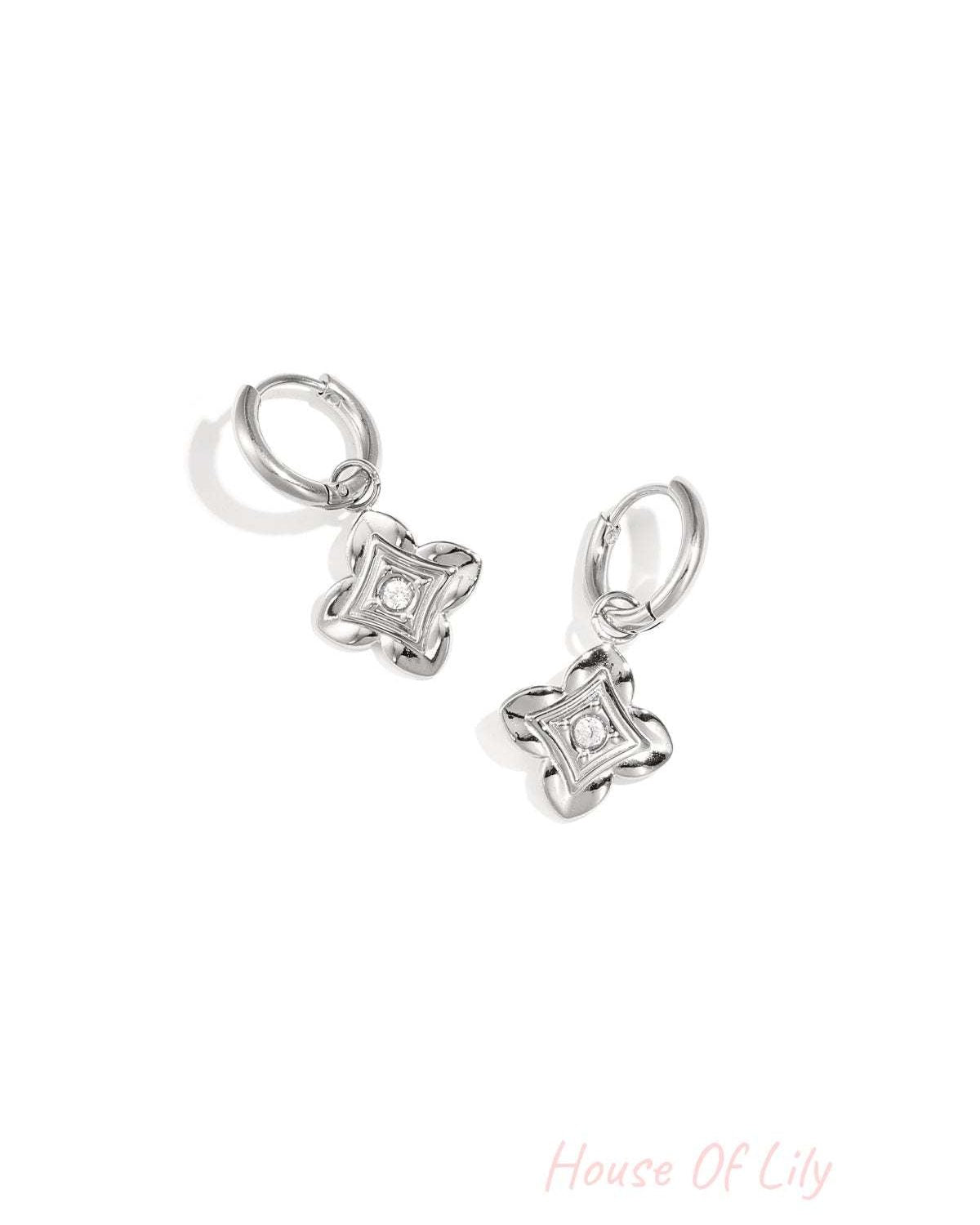 Close-up of silver floral drop earrings with zircon center on white background
