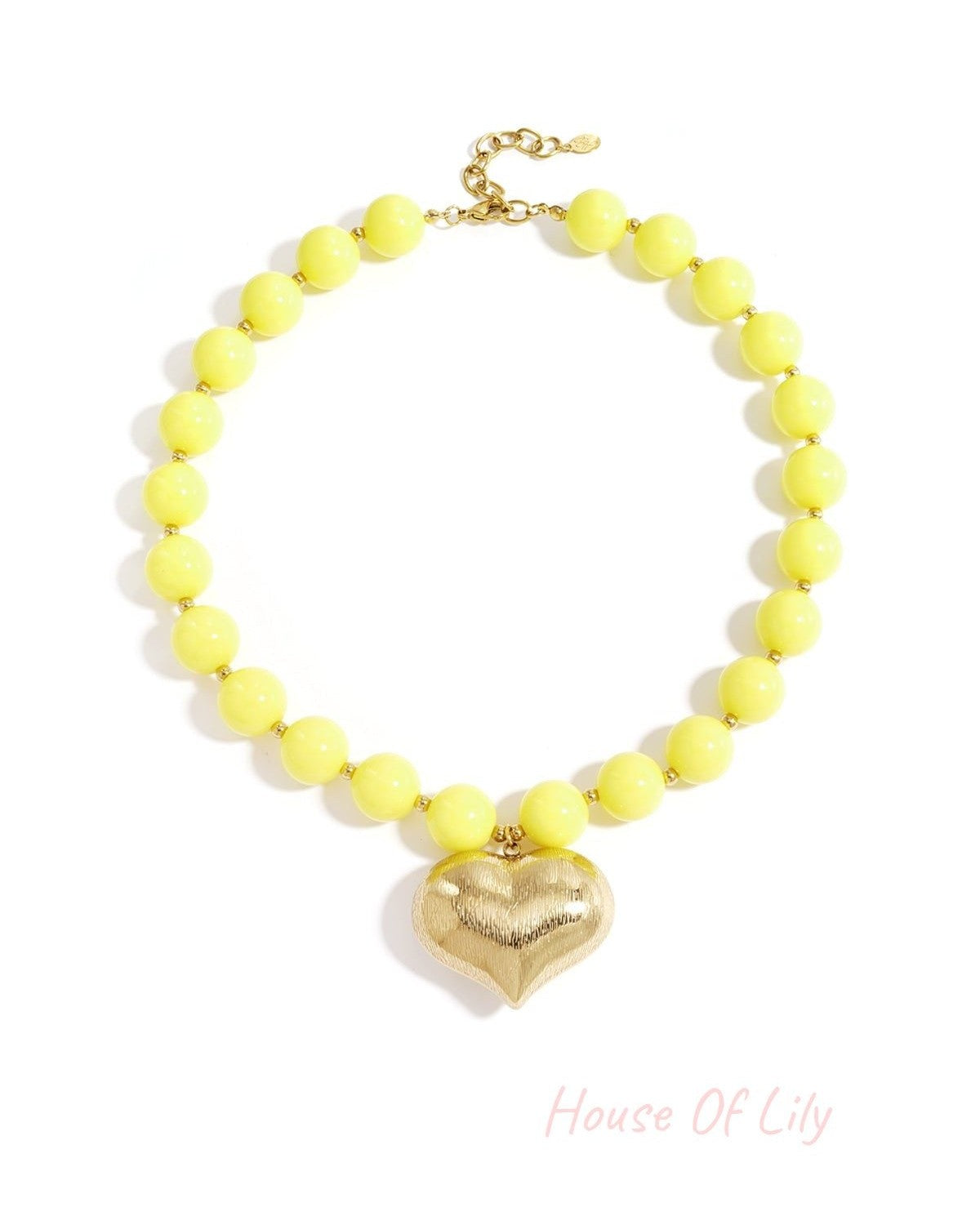 Chunky sunny yellow beaded necklace with textured gold heart pendant laid flat