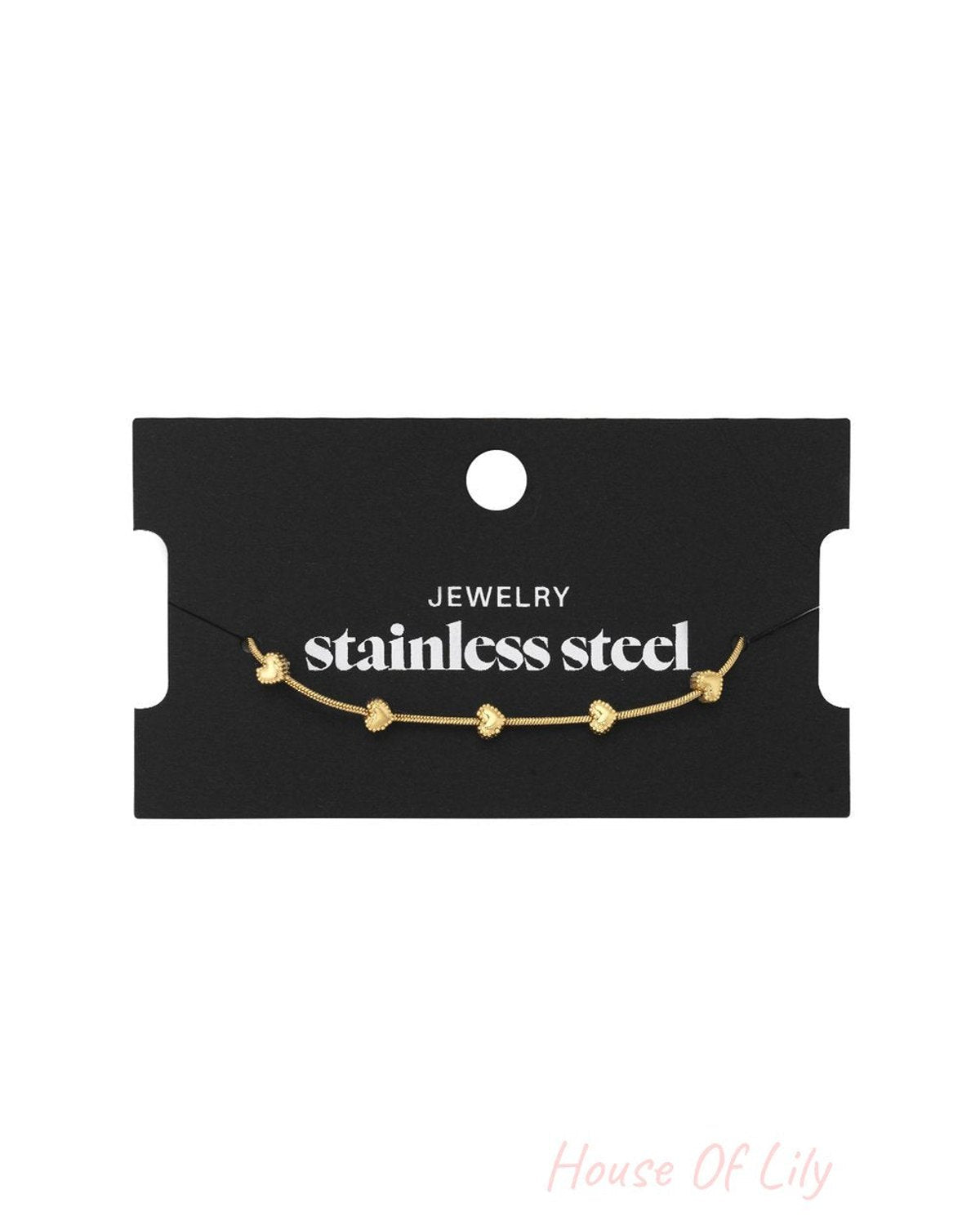 Gold-tone stainless steel bangle featuring delicate heart charms on a thin chain, displayed on black packaging.