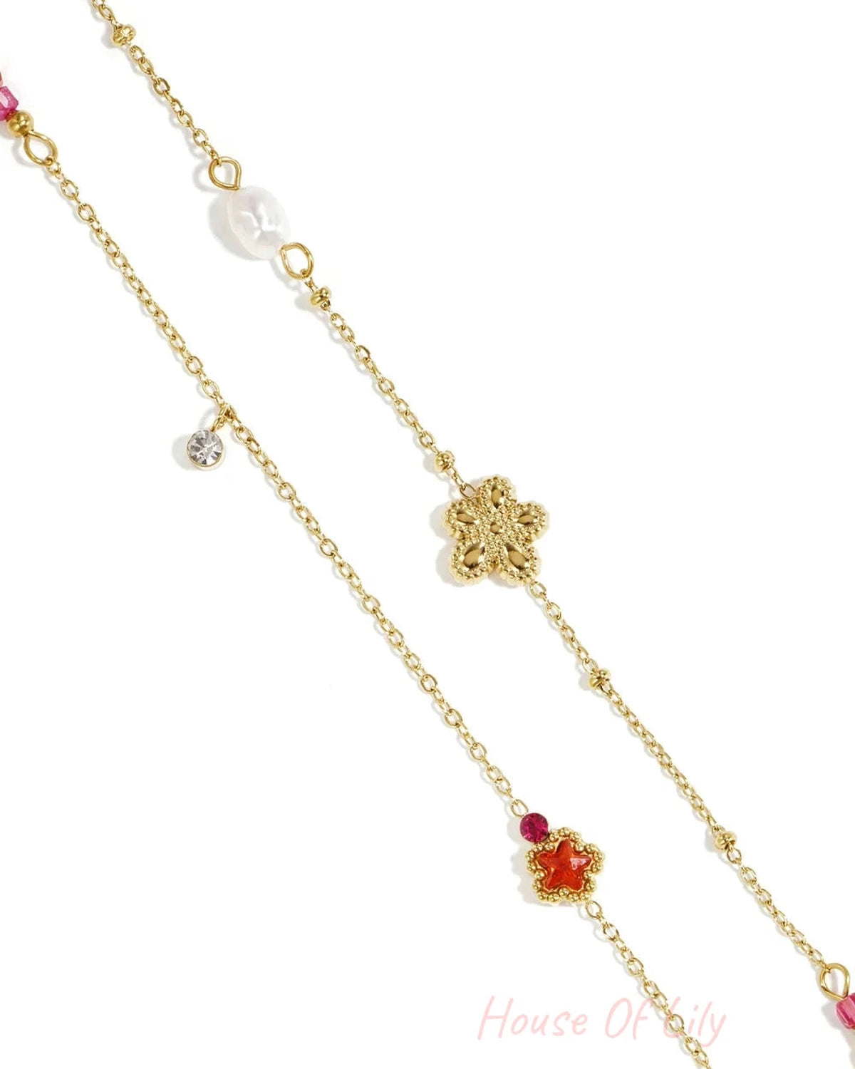 Gold charm bracelet featuring flower, star, pearl, and crystal charms on a delicate gold chain.