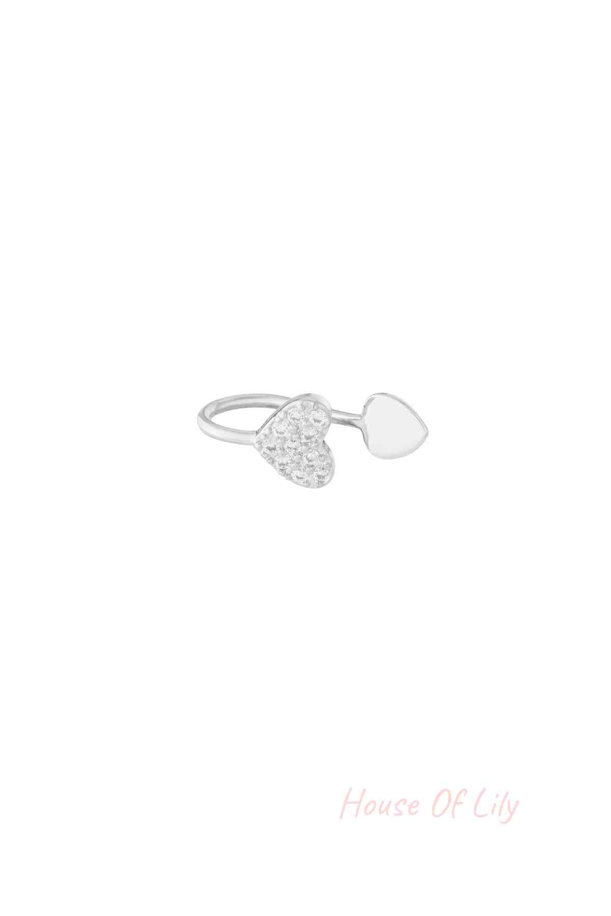 Close-up image of a silver-tone open heart ear cuff featuring one heart adorned with clear zircon crystals and the other smooth and polished