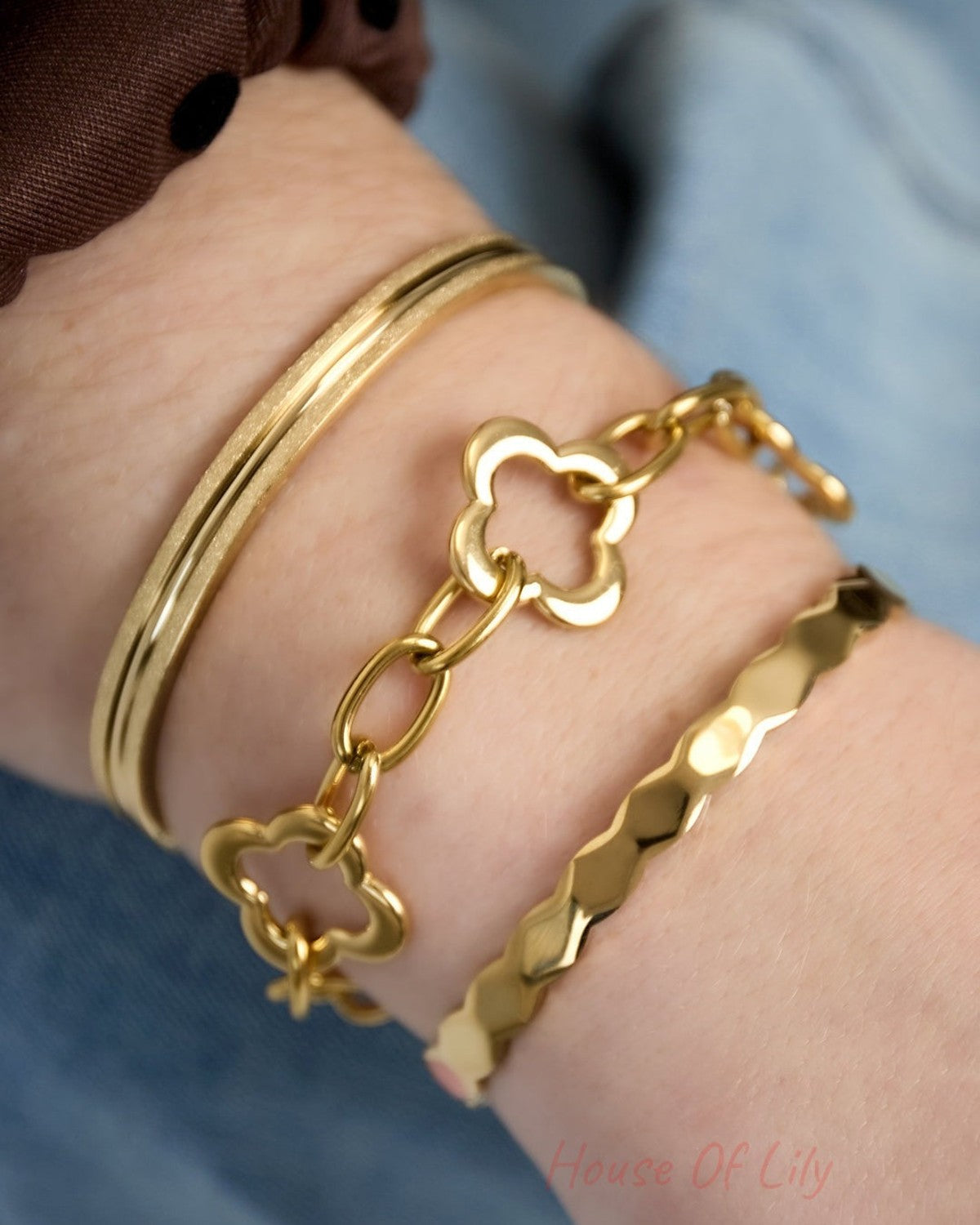 Close-up of gold-tone textured bangle bracelet layered with two gold bracelets on wrist