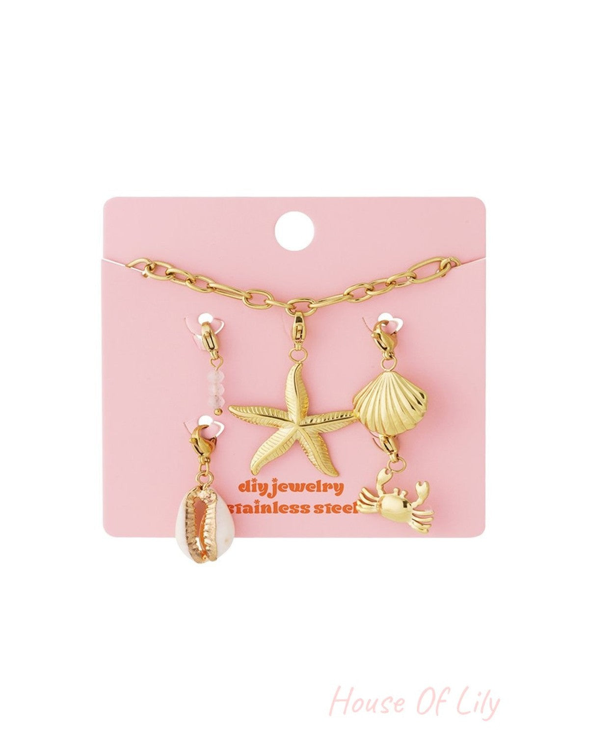 Gold chain bracelet with beach-themed charms including a starfish, seashell, and crab on a pink display card.