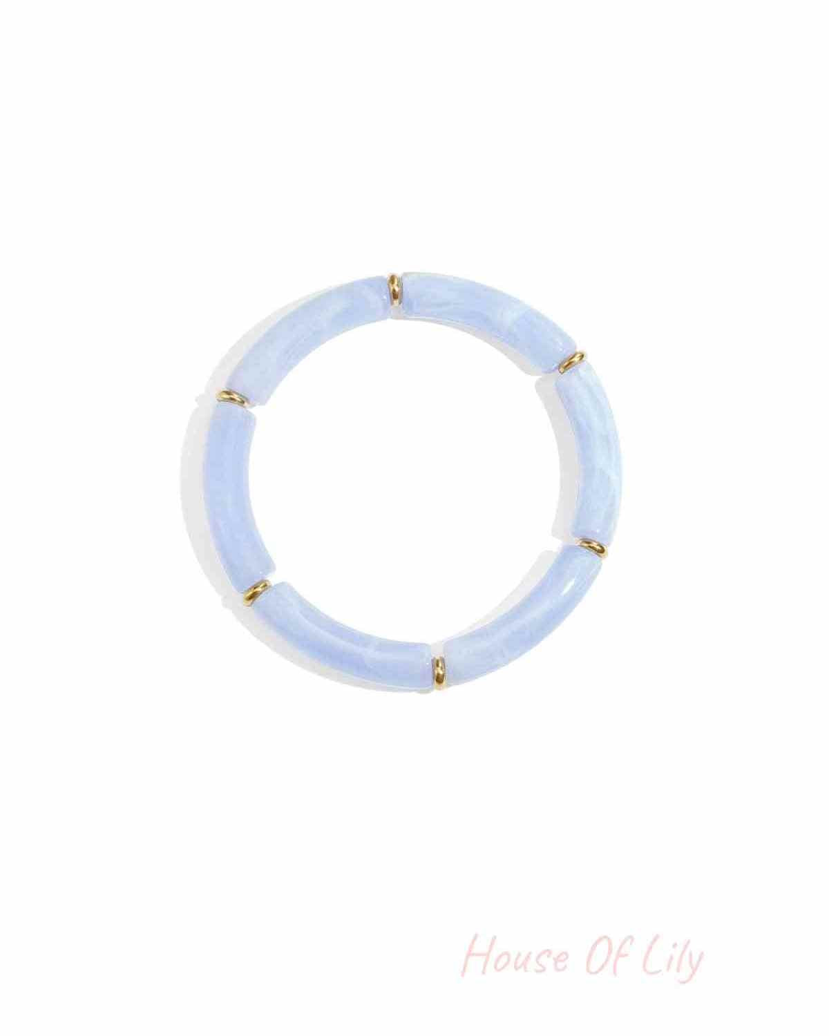 Baby blue resin tube bracelet with gold-tone ring spacers on white background